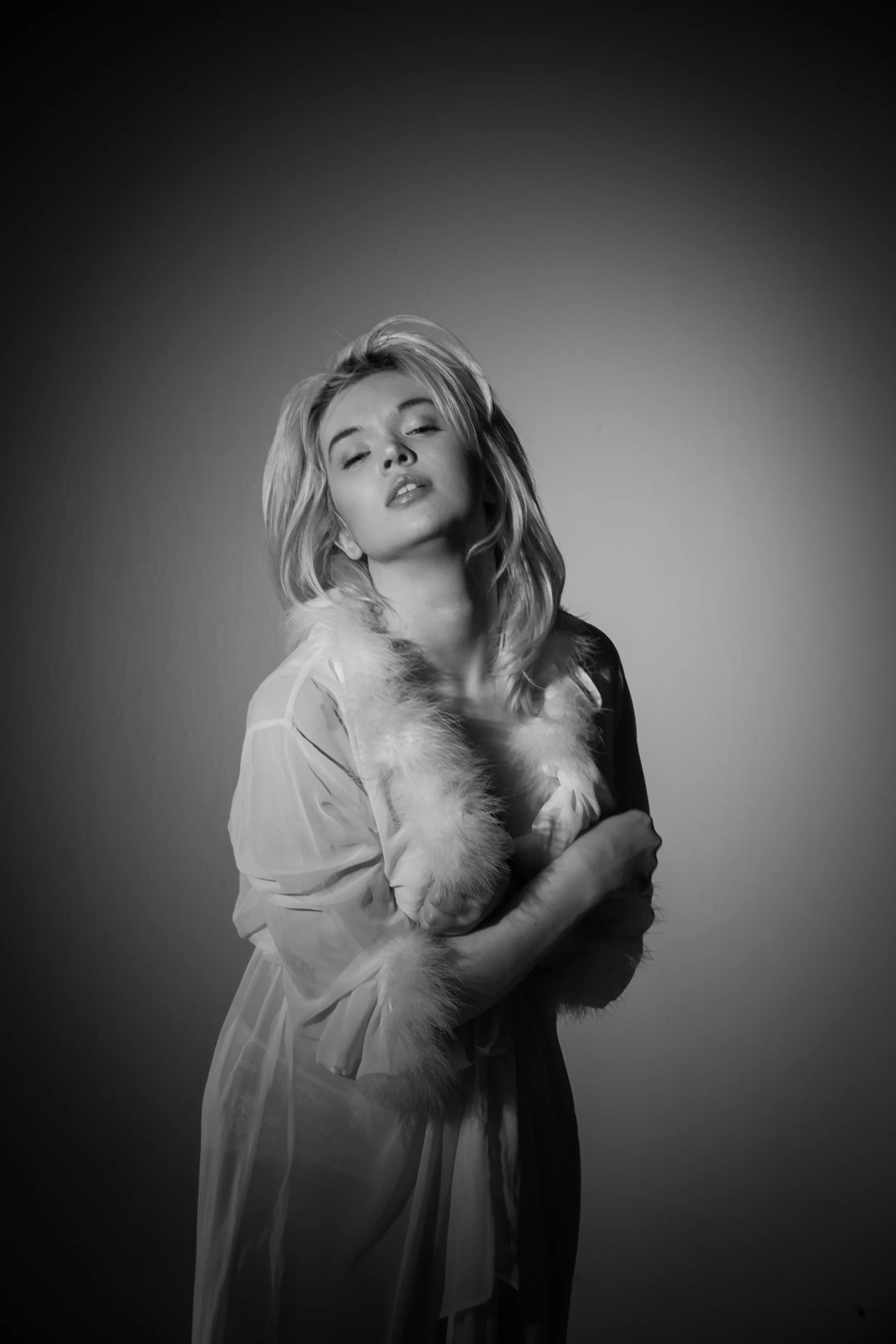 Black and white classic Hollywood glamour studio portrait of model Liz (@vegaharlan) by photographer Leonard 'Lenny Kats' Katsel. The image features dramatic soft lighting, a feather boa, and sheer robe, evoking the iconic style of Marilyn Monroe and