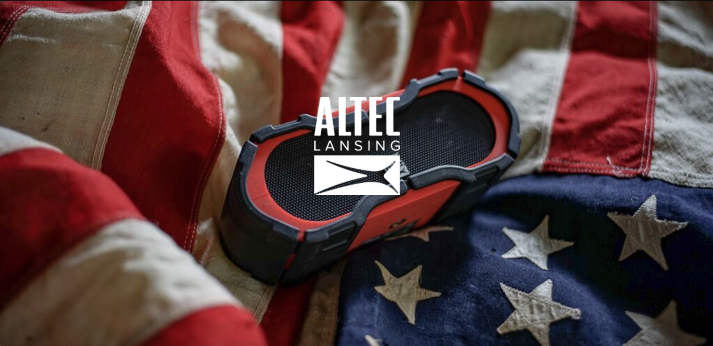 Altec Lansing red and black waterproof Bluetooth speaker resting on a vintage American flag, product photography by Leonard Katsel | Lenny Kats