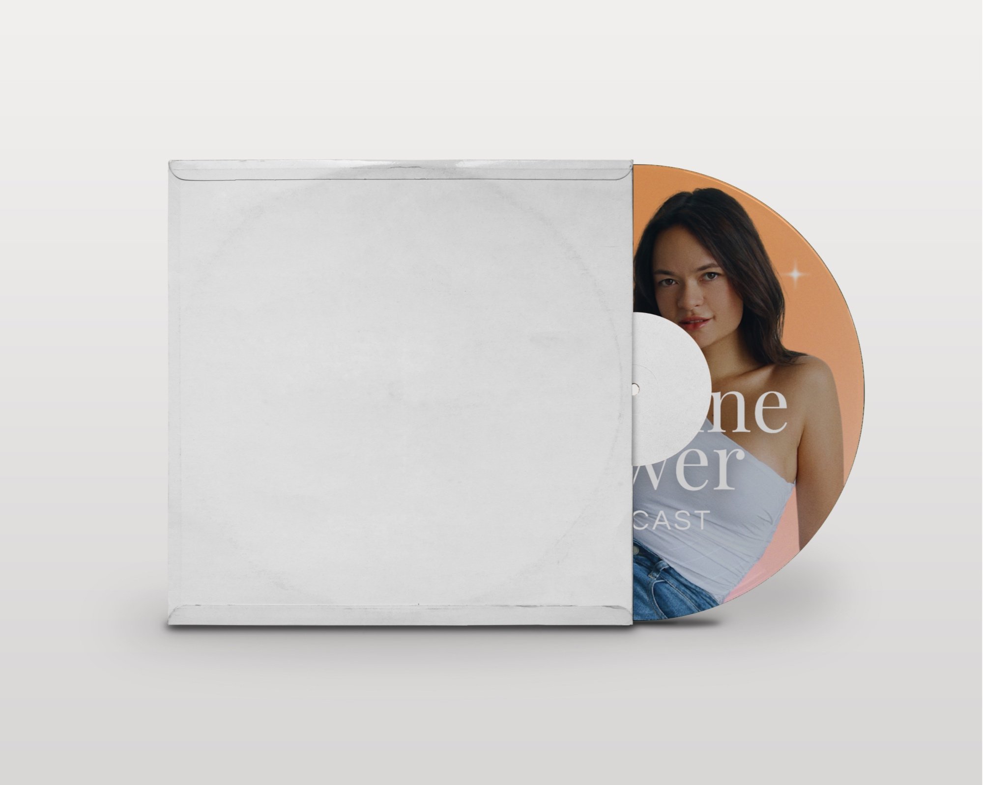 A partially opened white cardboard box revealing a magazine or poster of a woman with dark hair, wearing a white top and blue jeans, on a peach-colored background.