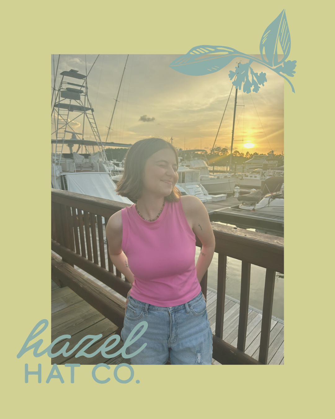 A woman with short brown hair wearing a pink sleeveless top and denim shorts standing on a wooden dock with boats and sailboats in the background at sunset, with light green digital border and blue floral graphic overlay.