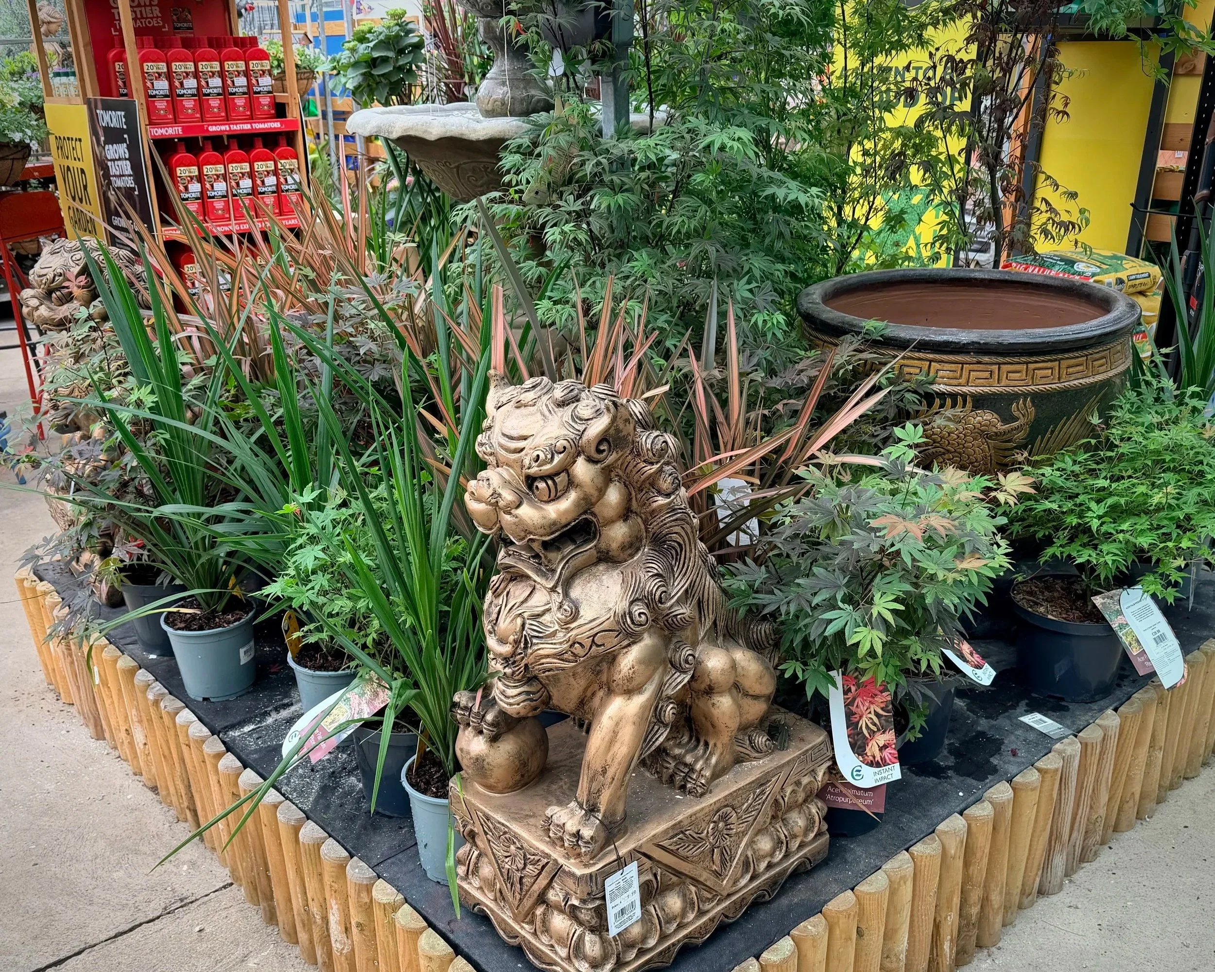 A display of potted plants, statues, and garden ornaments on a wooden table in a garden store.