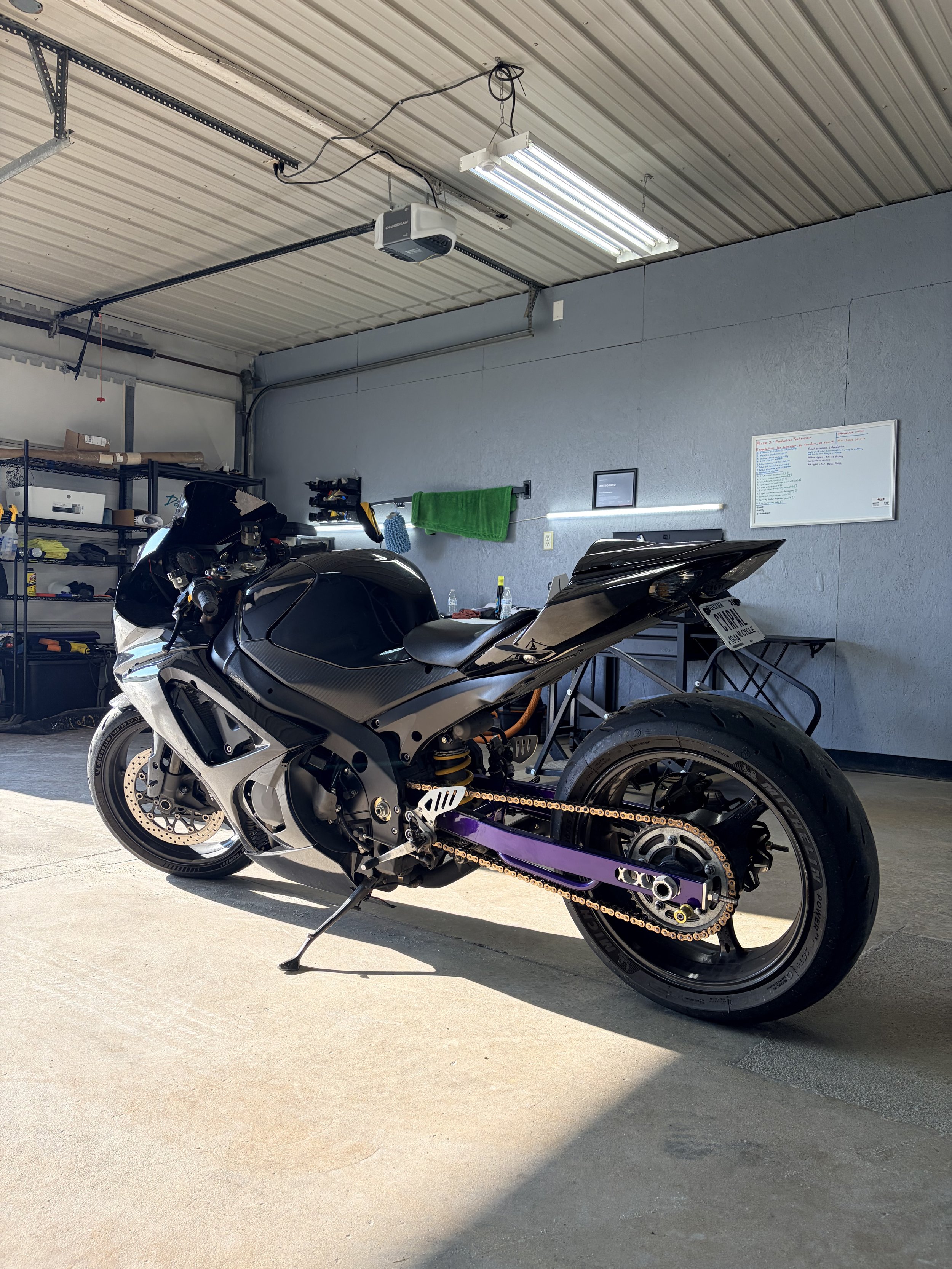 A black and white motorcycle parked inside a garage next to a workbench and shelving unit.