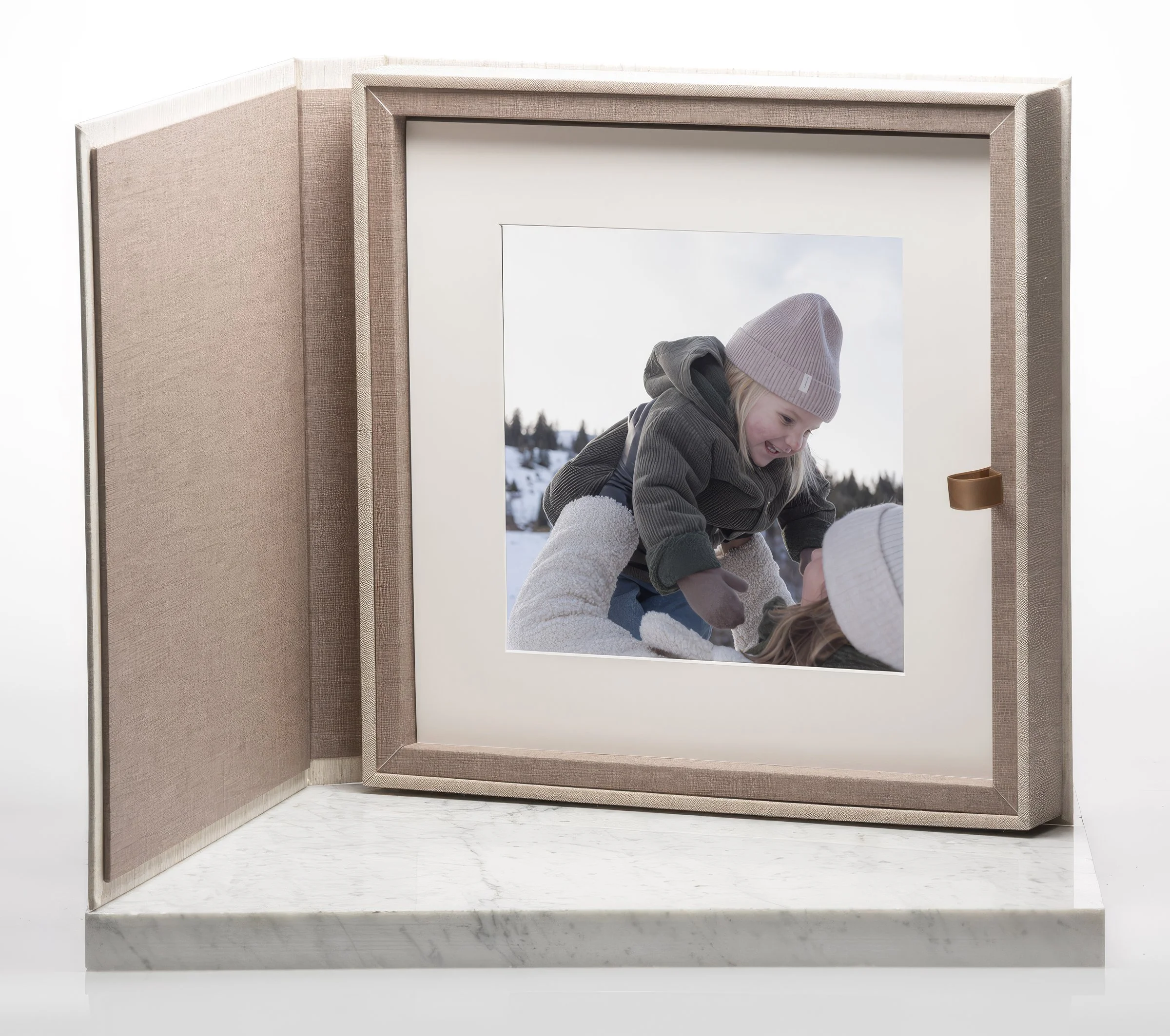 Linen folio box open to a framed winter portrait of parent and child — premium family portraits by The Oak Studio