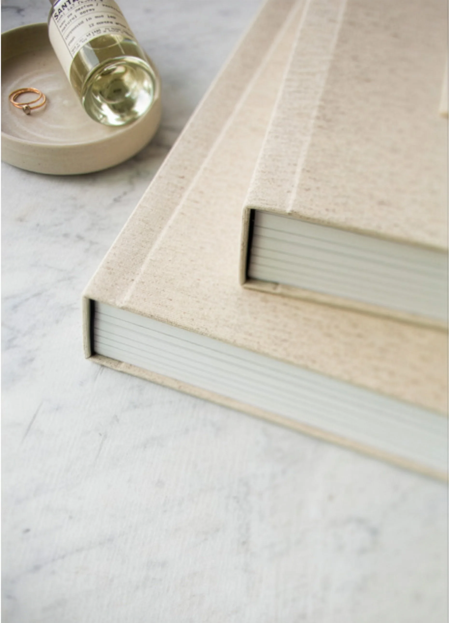 Two cream linen heirloom albums stacked showing spine detail — premium fine art albums by The Oak Studio