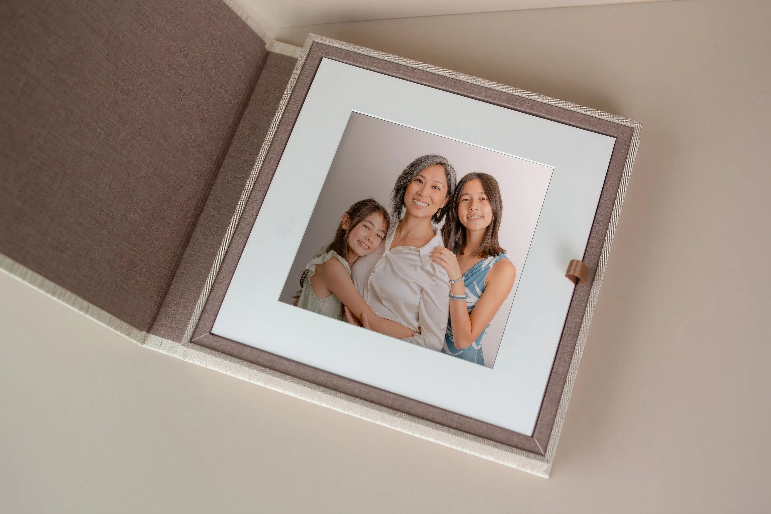 Linen-bound folio box open to reveal a framed family portrait — premium heirloom presentation by The Oak Studio