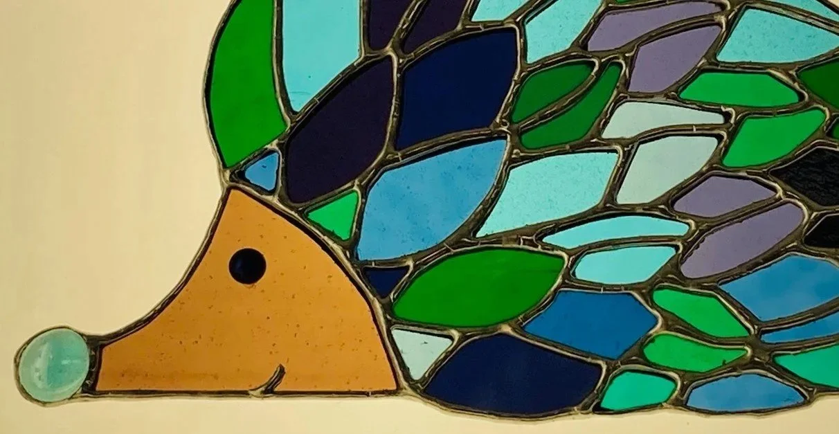 Stained glass hedgehog in greens, blue, and purples