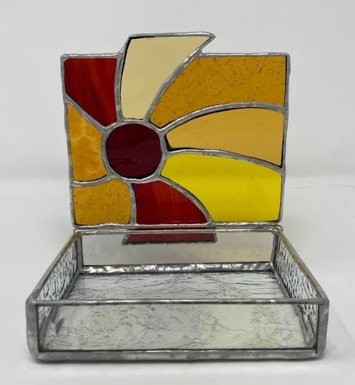 Stained glass jewelry box featuring a red and orange sunburst lid design. 5 x 5 x 1 inch. $125.