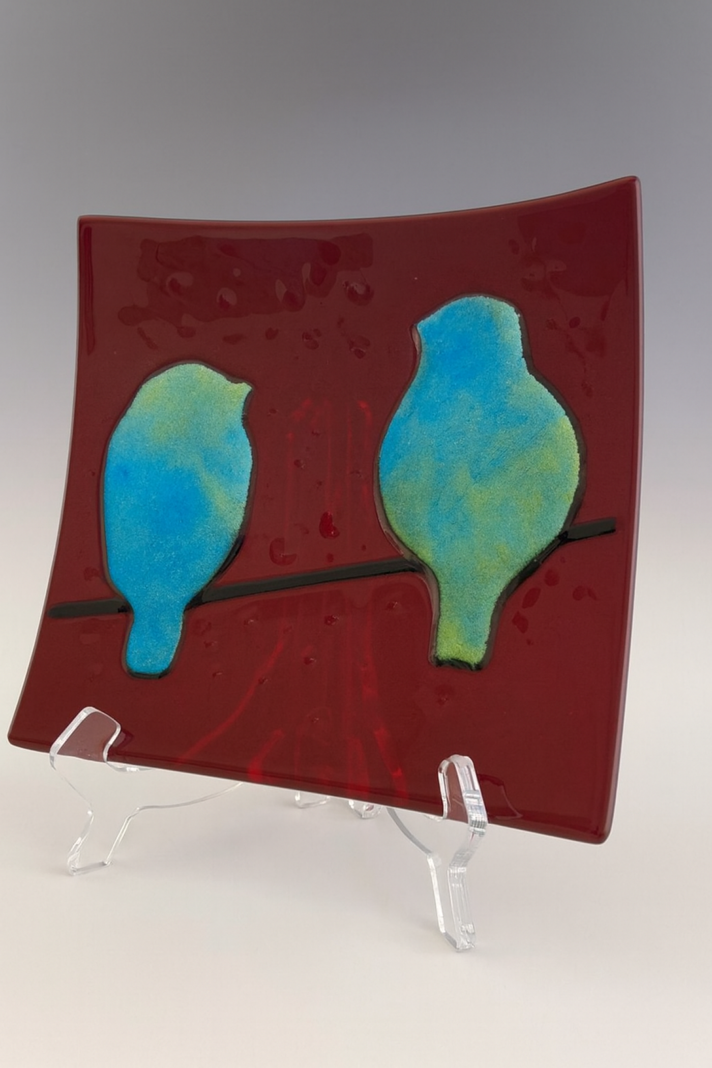 Square fused glass plate with two iridescent bluebirds on a red background