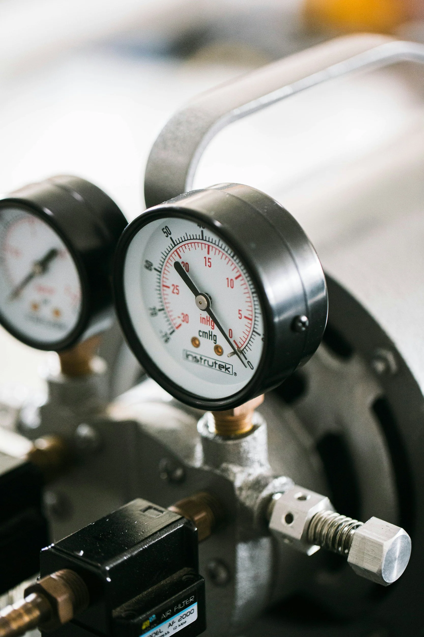 Close-up of pressure gauges, metallic pipes, and machinery parts in an industrial or laboratory setting.