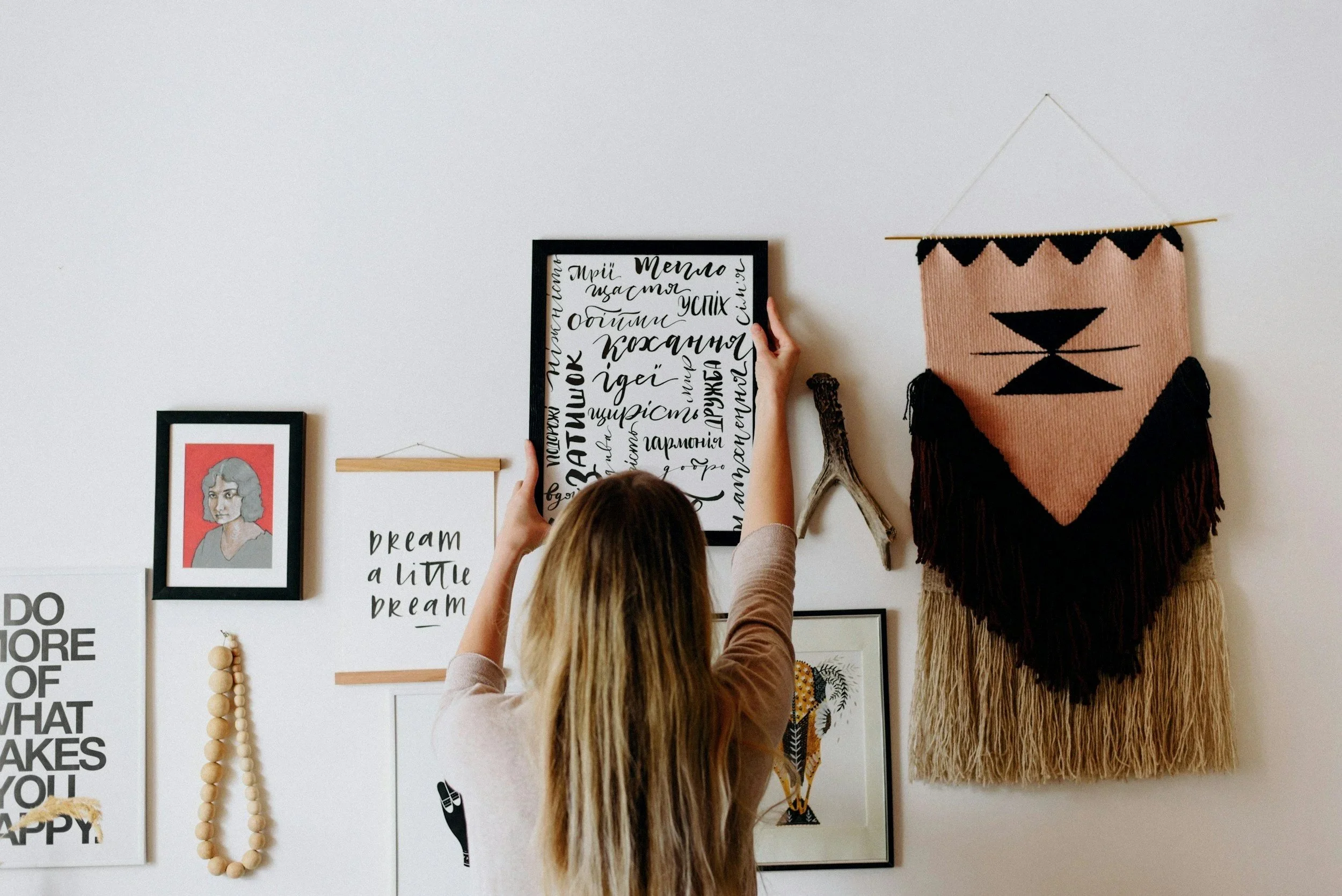 A woman having a piece of art framed on the wall