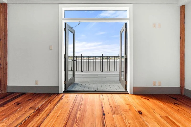 Riverview Penthouse at Josephine Lofts room with hardwood floors and double doors opening to a private balcony.