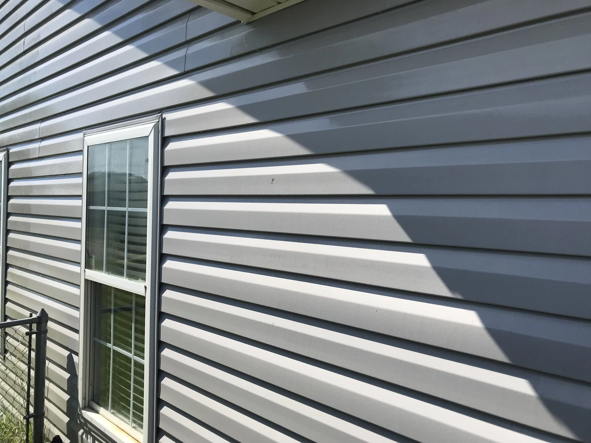 Exterior view of a house with grey horizontal vinyl siding and a sliding glass door.