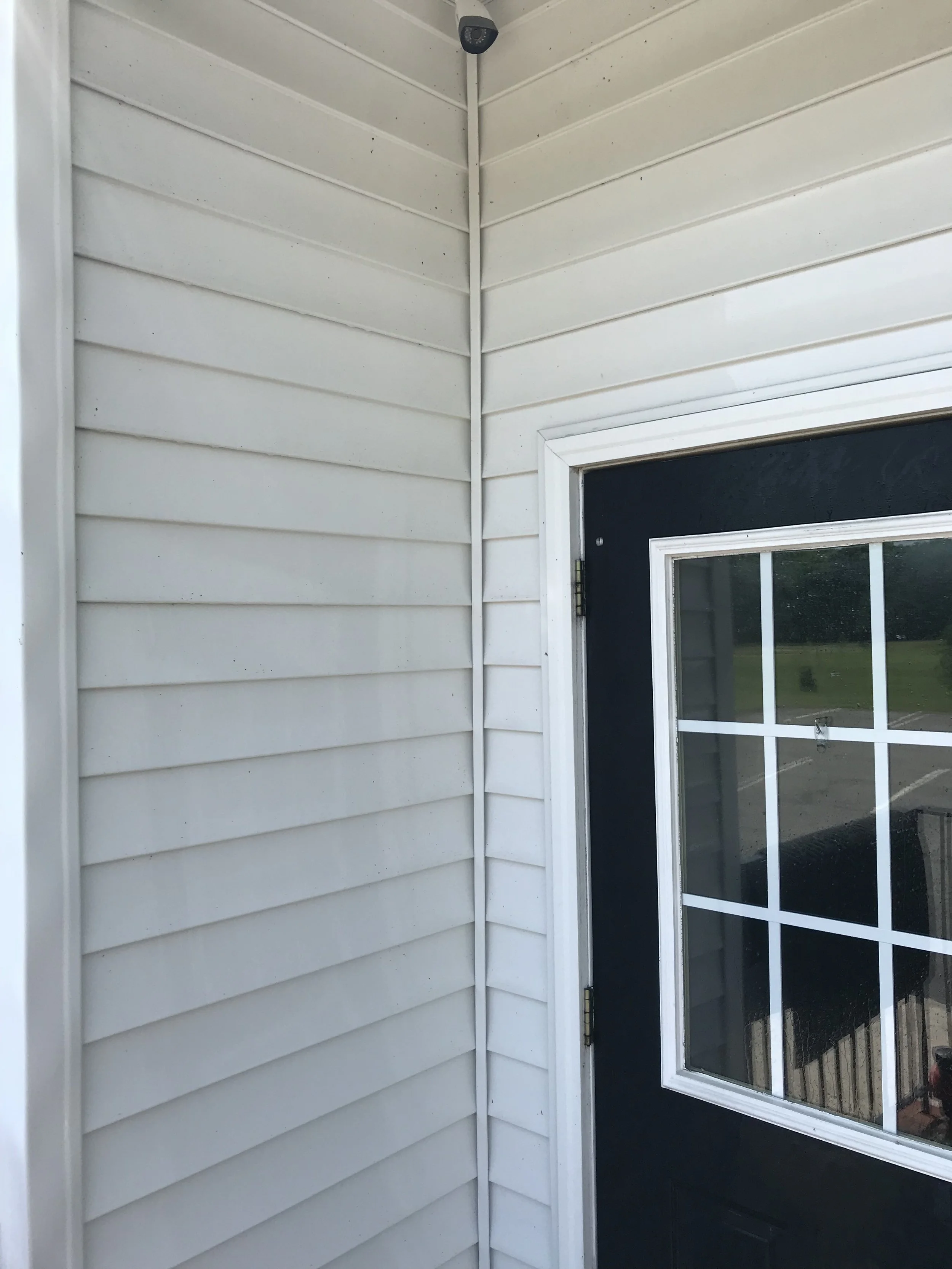Image of an exterior corner of a house showing beige horizontal siding and a sliding glass door with a dark frame.