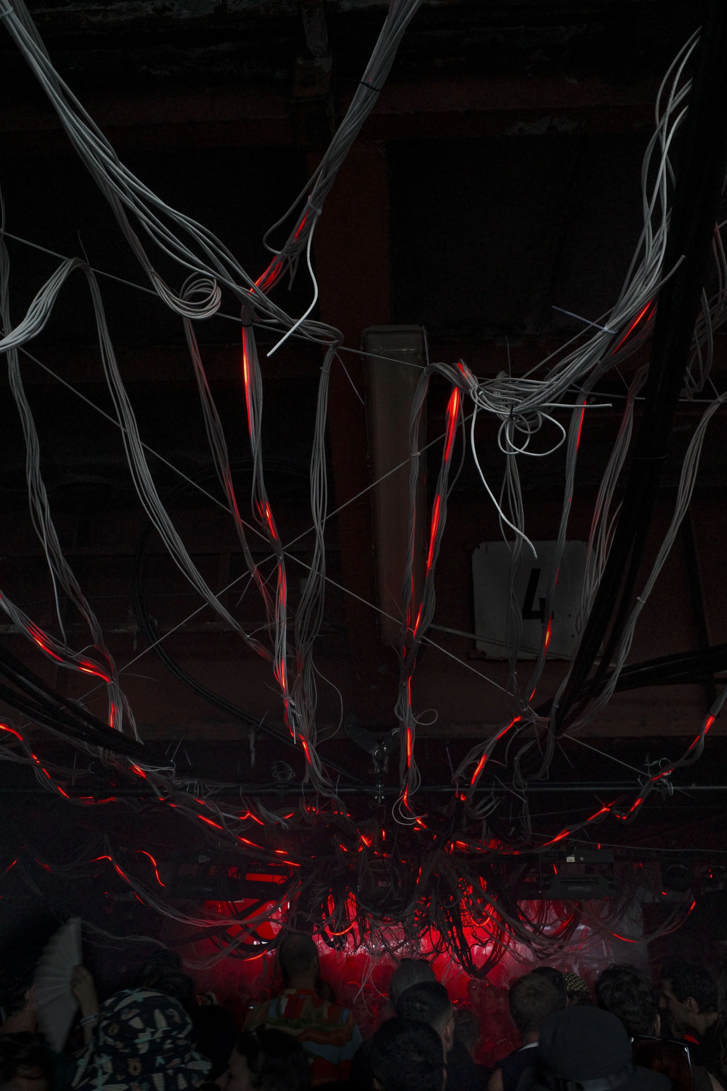 Crowd of people on a stage with intertwined wires and red LED lights at Stone Techno Festival.