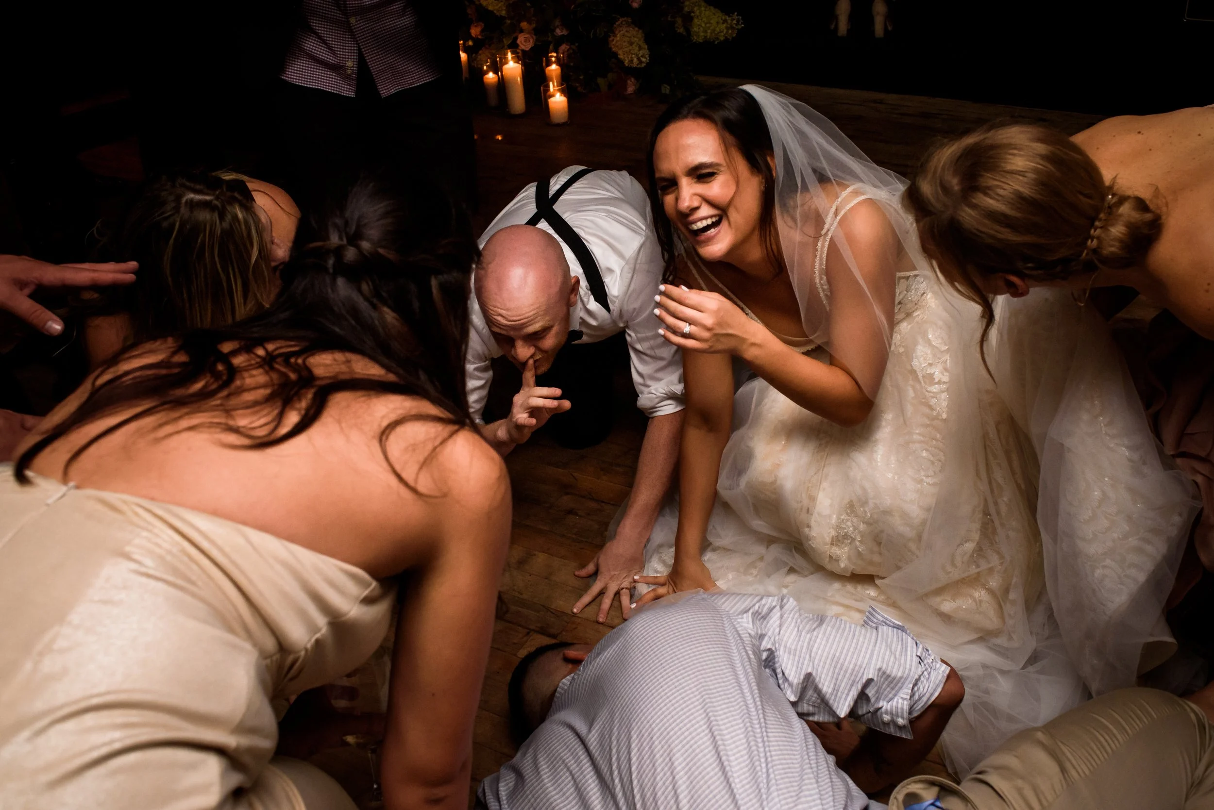 Bride and groom laughing as they crouch down on the dance floor with guests at a St-Henri, Montreal wedding reception.
