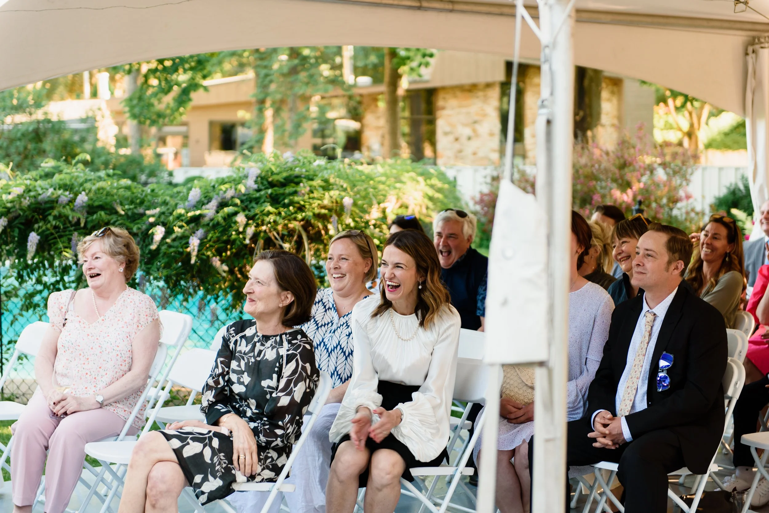 Wedding guests seated at outdoor wedding ceremony laughing and smiling