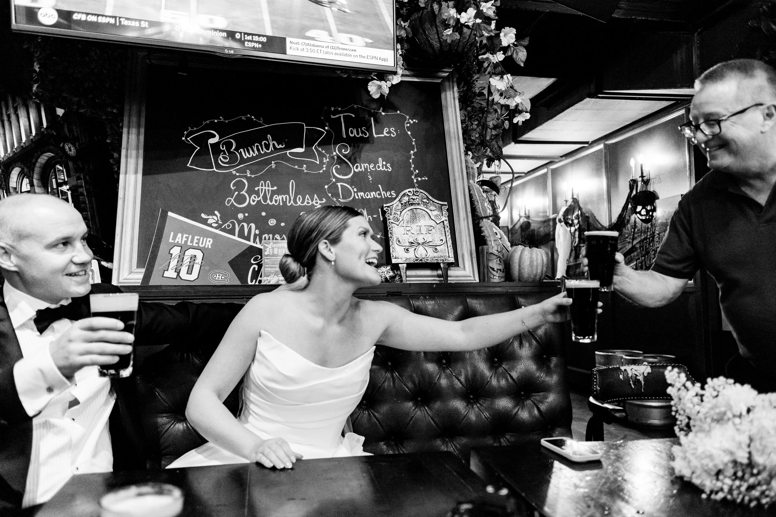 Bride and groom taking a post-ceremony break at a Montreal pub, sitting together as they enjoy a pint of Guinness before their reception.