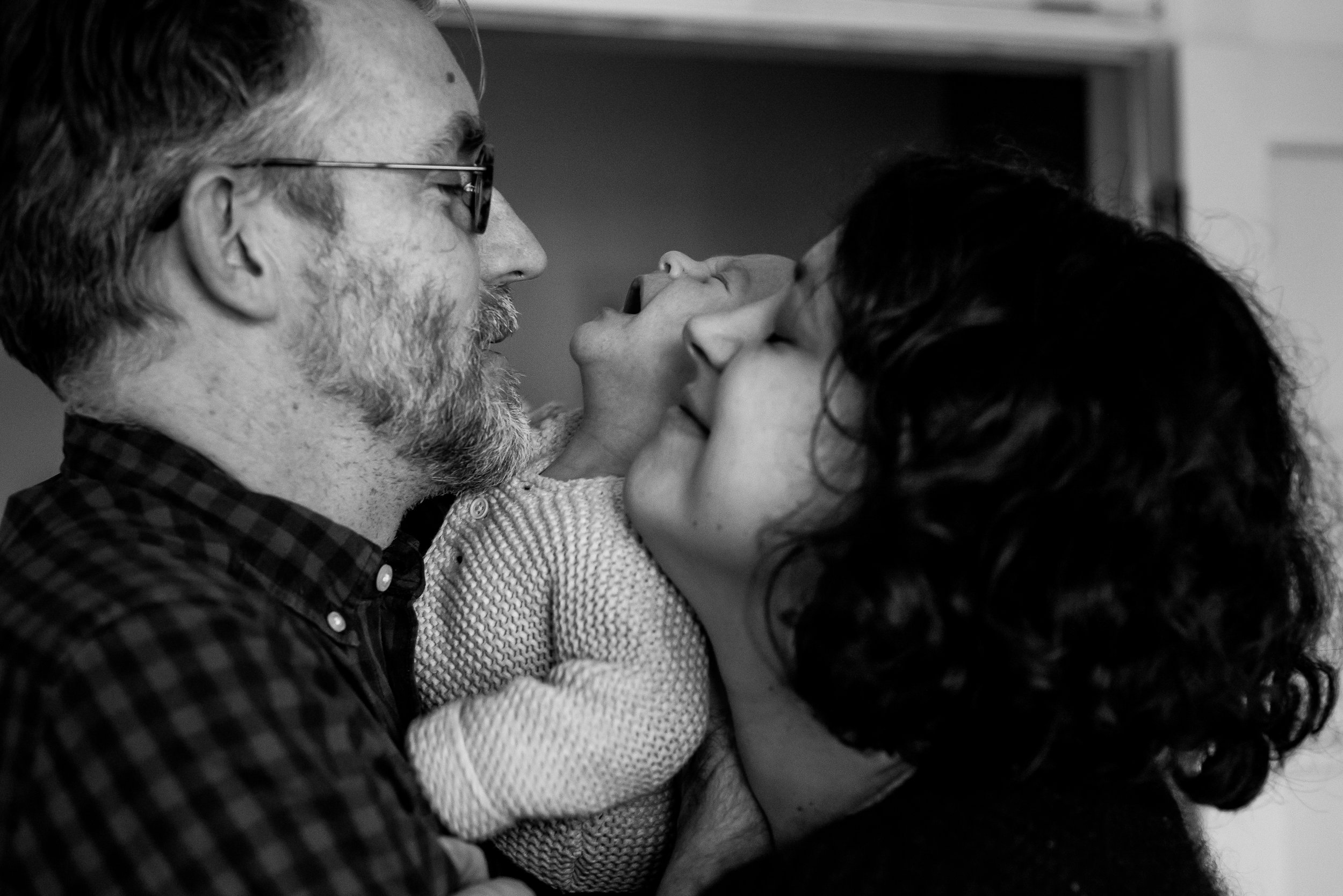 A black and white photo of a man with glasses and a beard, and a woman with curly hair, both leaning in and touching foreheads with their eyes closed, sharing an intimate and tender moment.