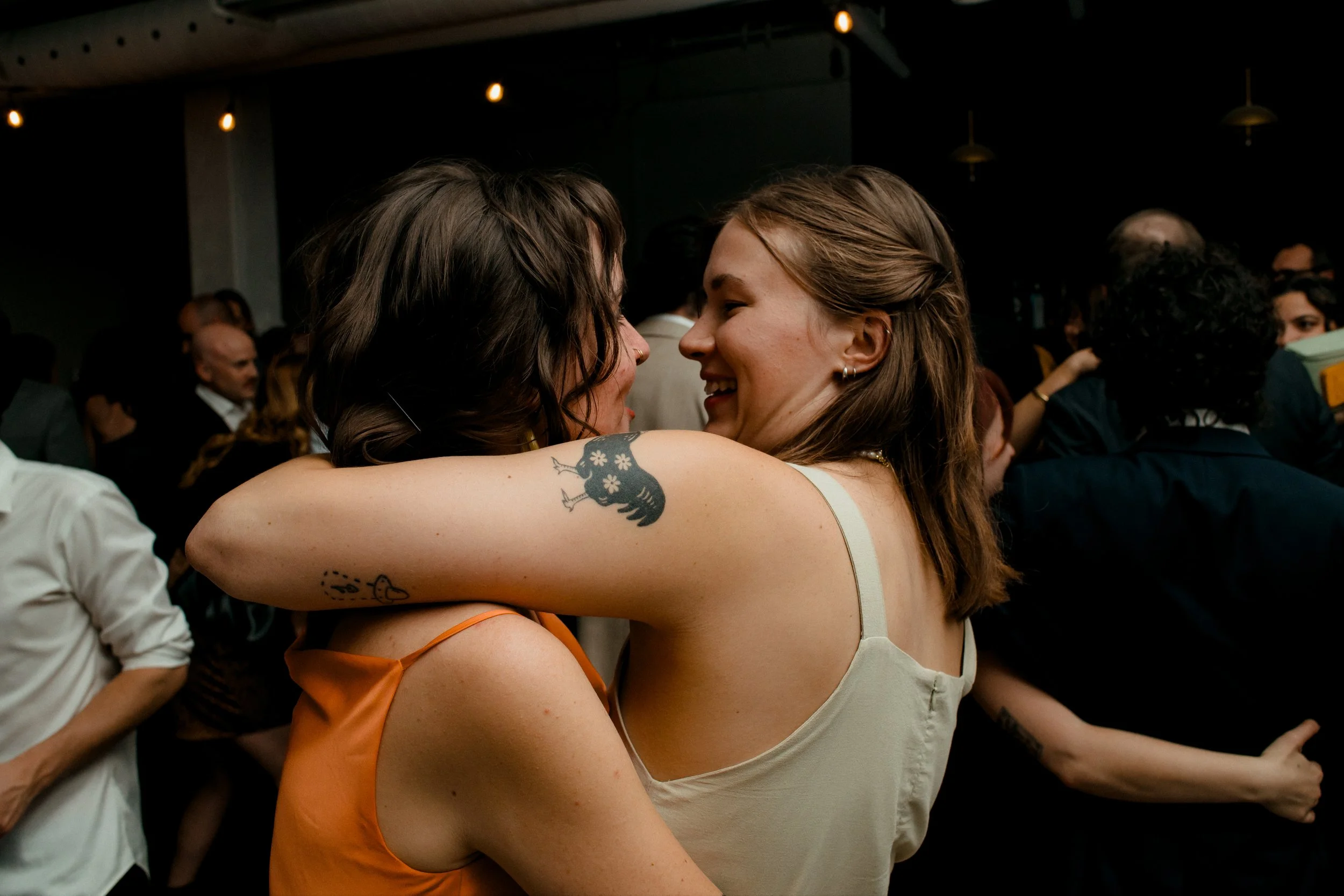 Two women embrace on dance floor smiling at one another