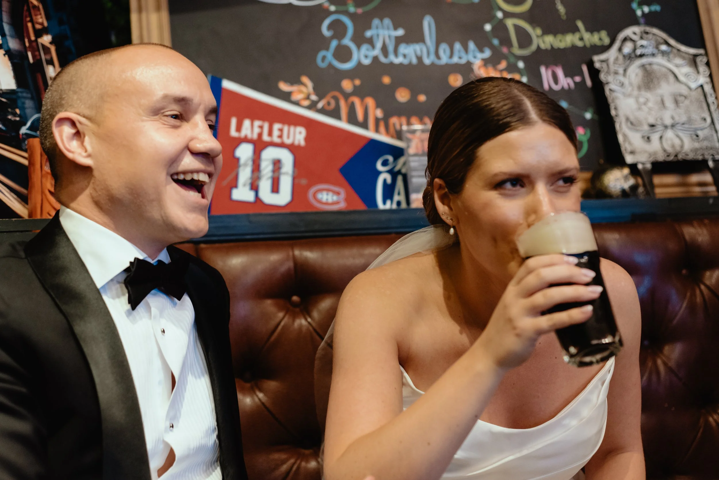 Bride and groom taking a post-ceremony break at a Montreal pub, sitting together as they enjoy a pint of Guinness before their reception.