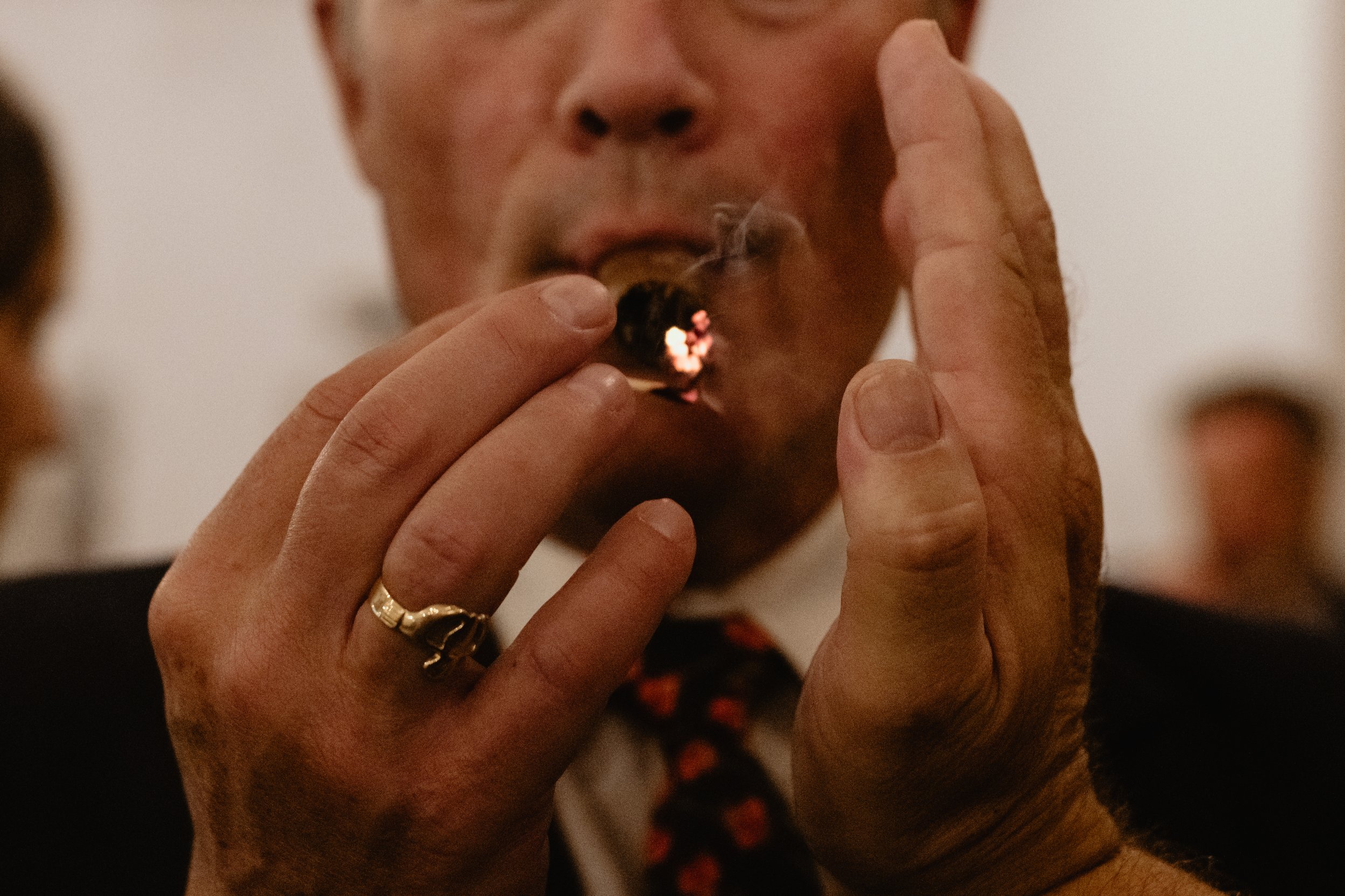 Close-up of the groom's father lighting a cigar, with his Claddagh wedding ring clearly visible on his hand.
