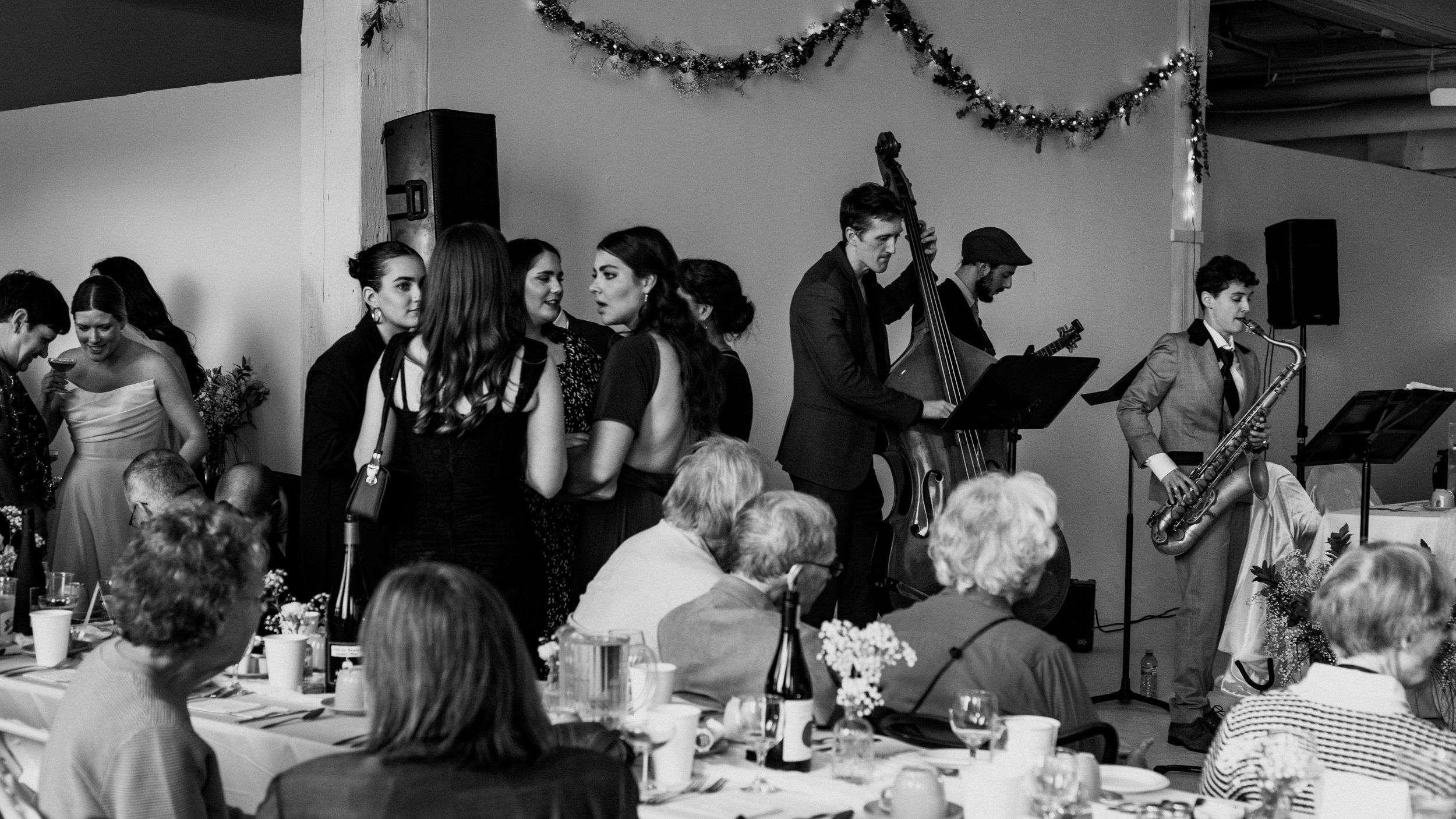 Wedding guests holding cocktails and socializing at an indoor Montreal wedding reception enjoying live music. 