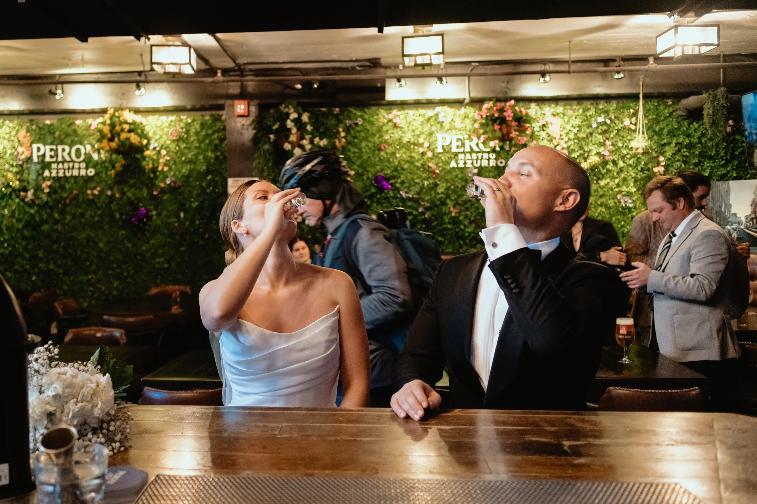 Bride and groom in wedding attire sharing a shot at Lord William Pub in Montreal.