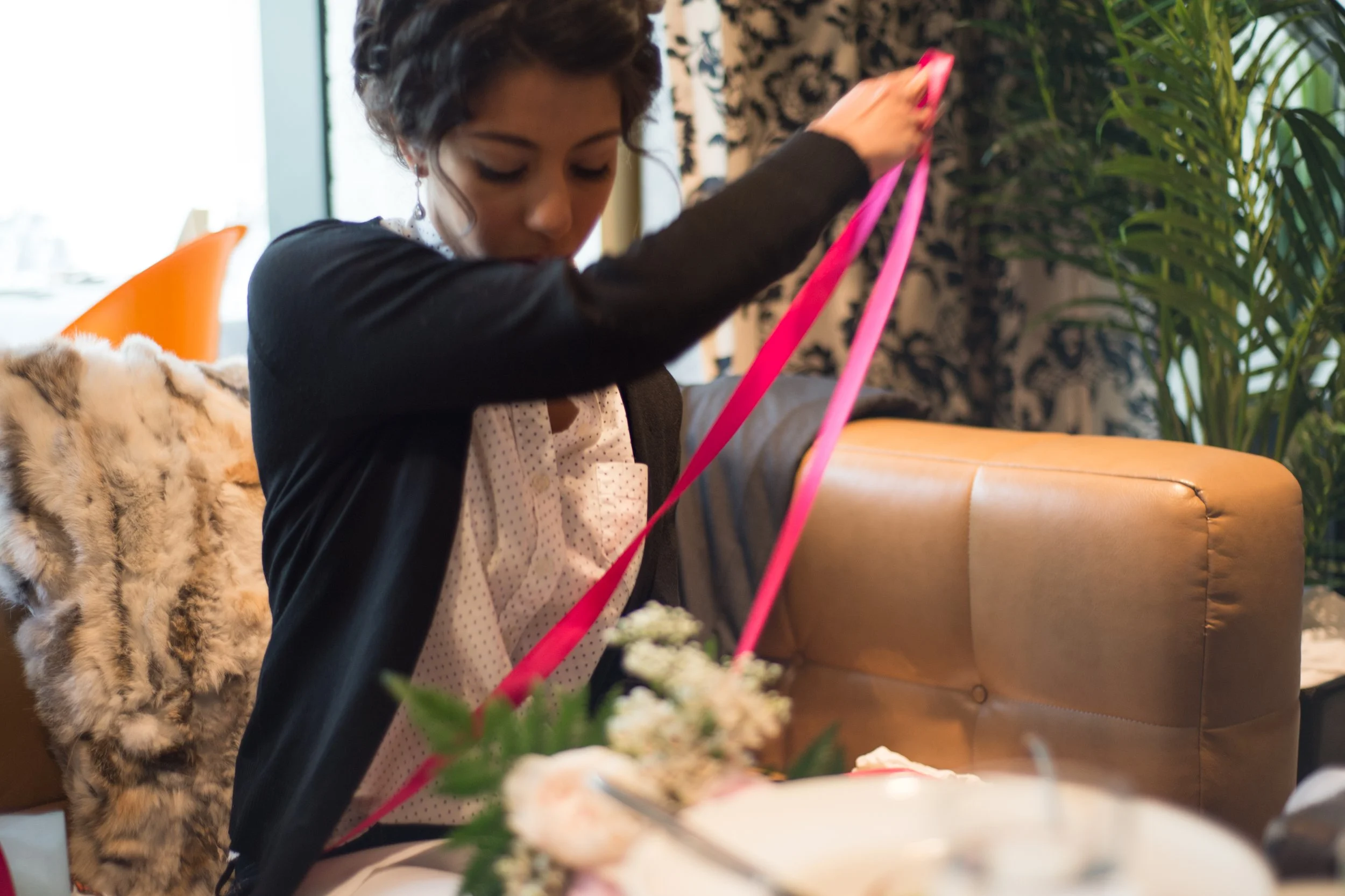 Woman wrapping hot pink ribbon around flower bouquet
