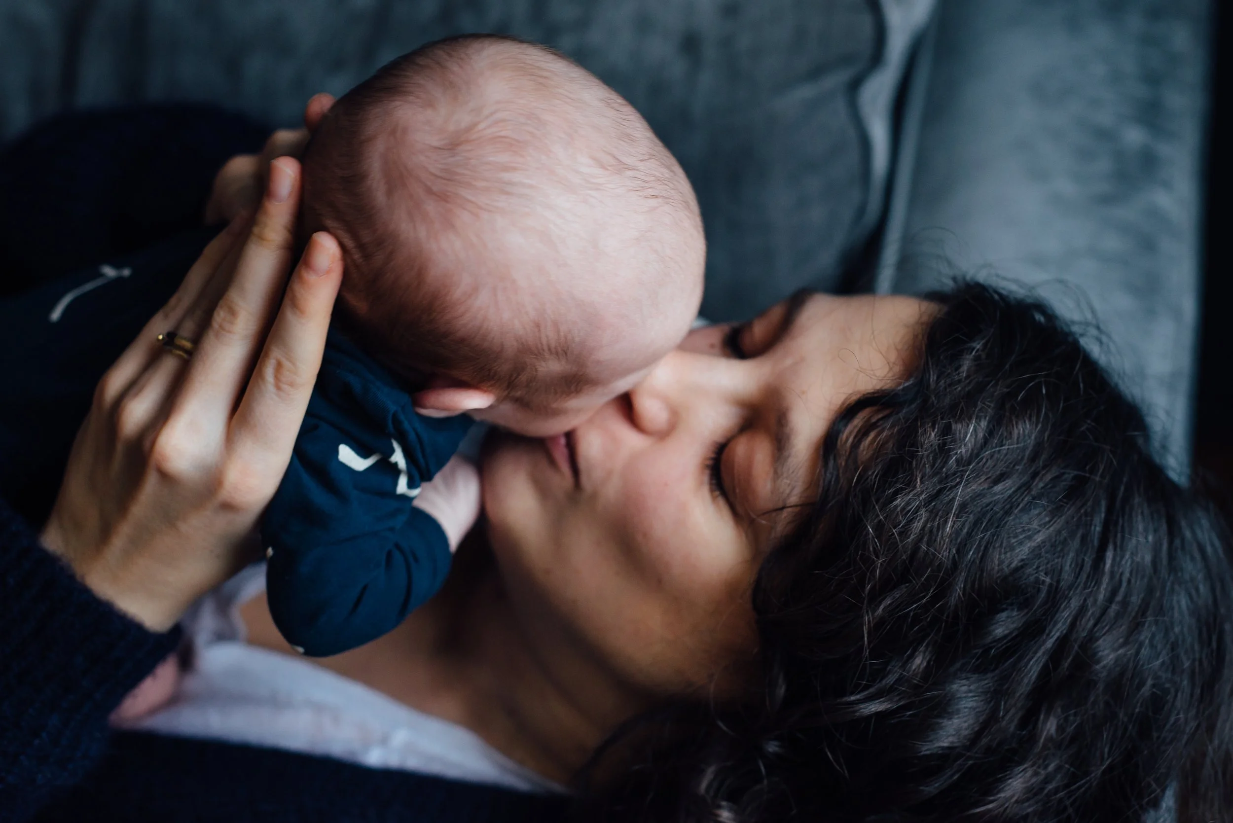 A baby and an adult sharing a kiss with the baby's hand on the adult's face.