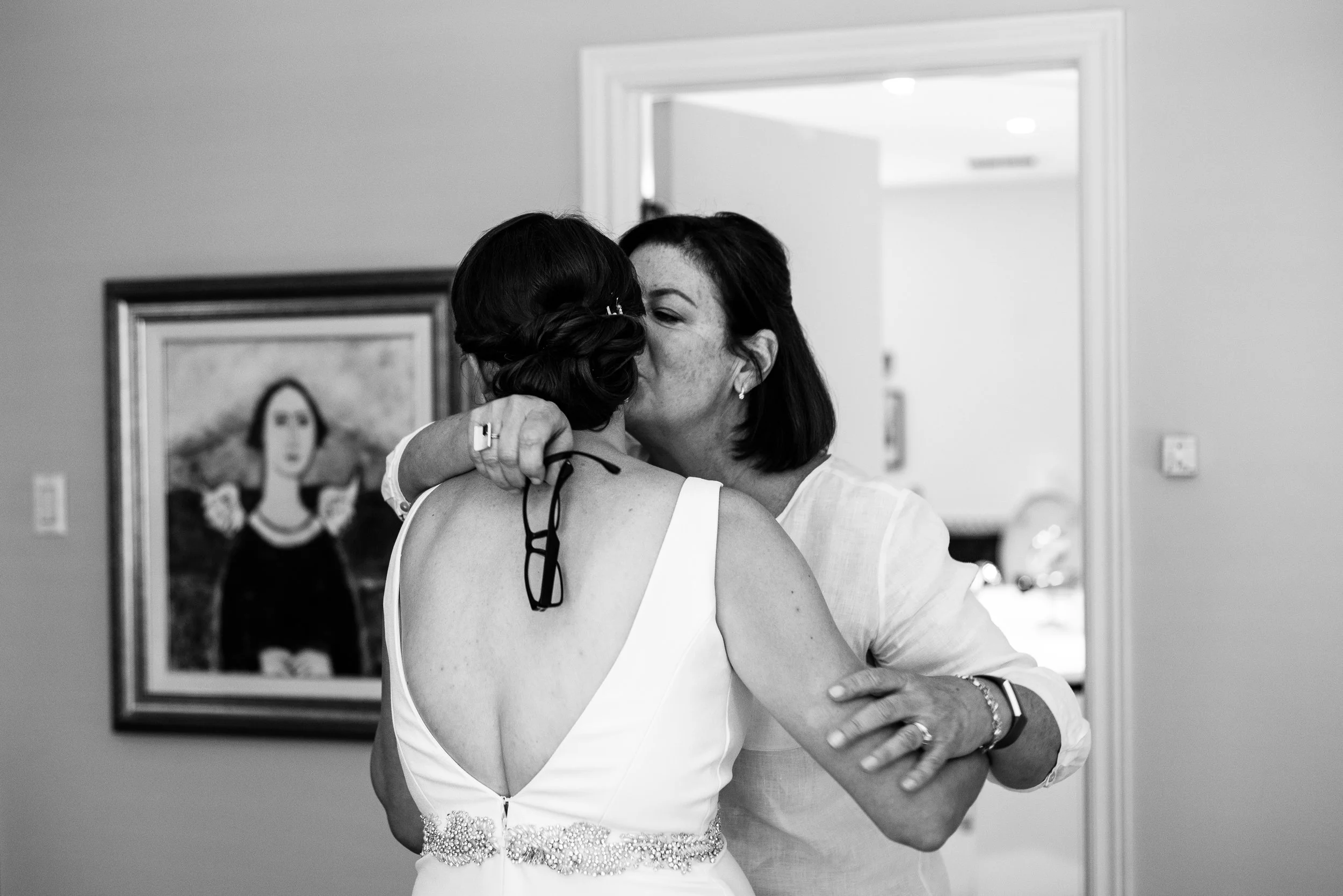 A bride shares an embrace with her mother as she gets ready for her wedding day.