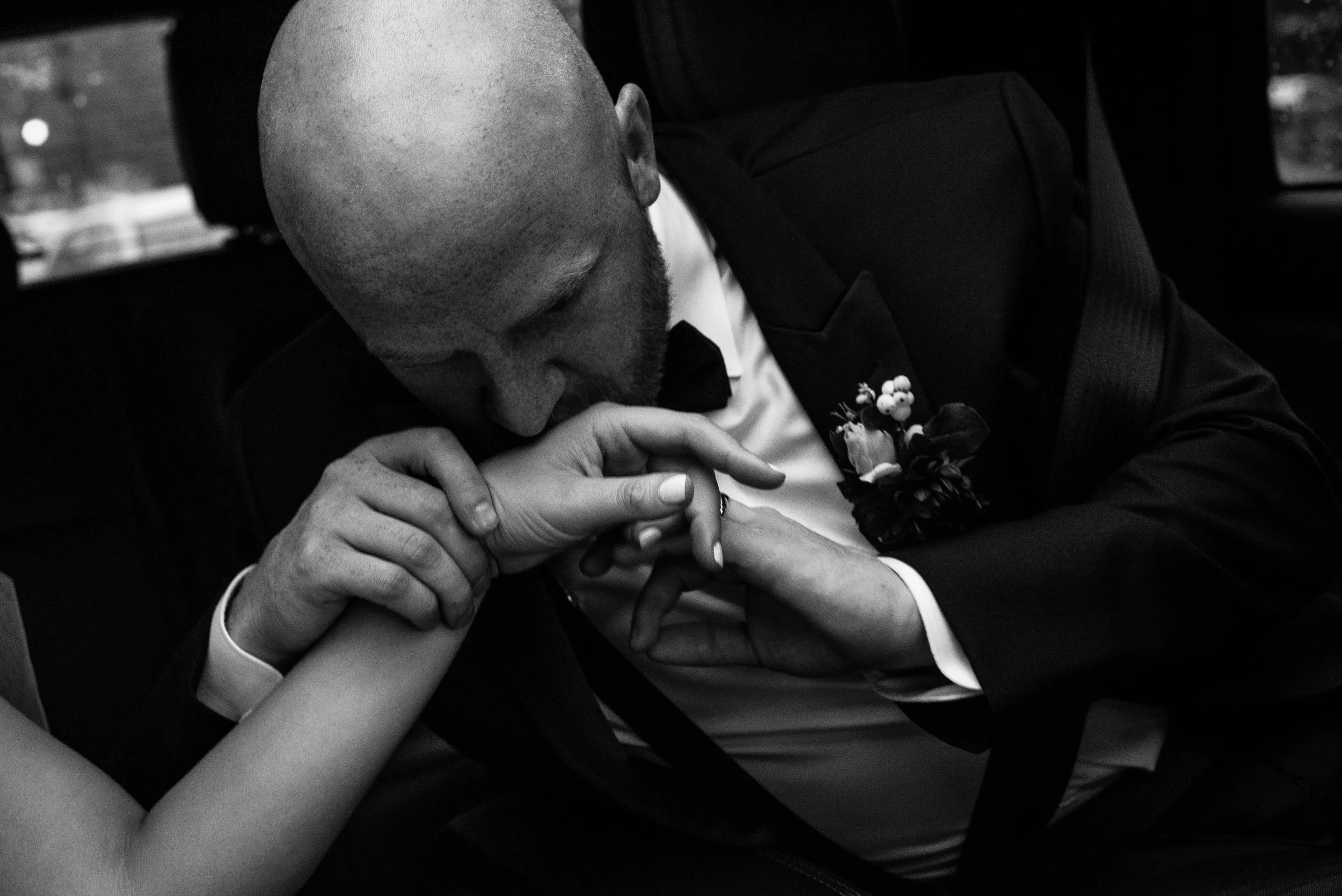 Black and white image of Groom kissing bride's hand