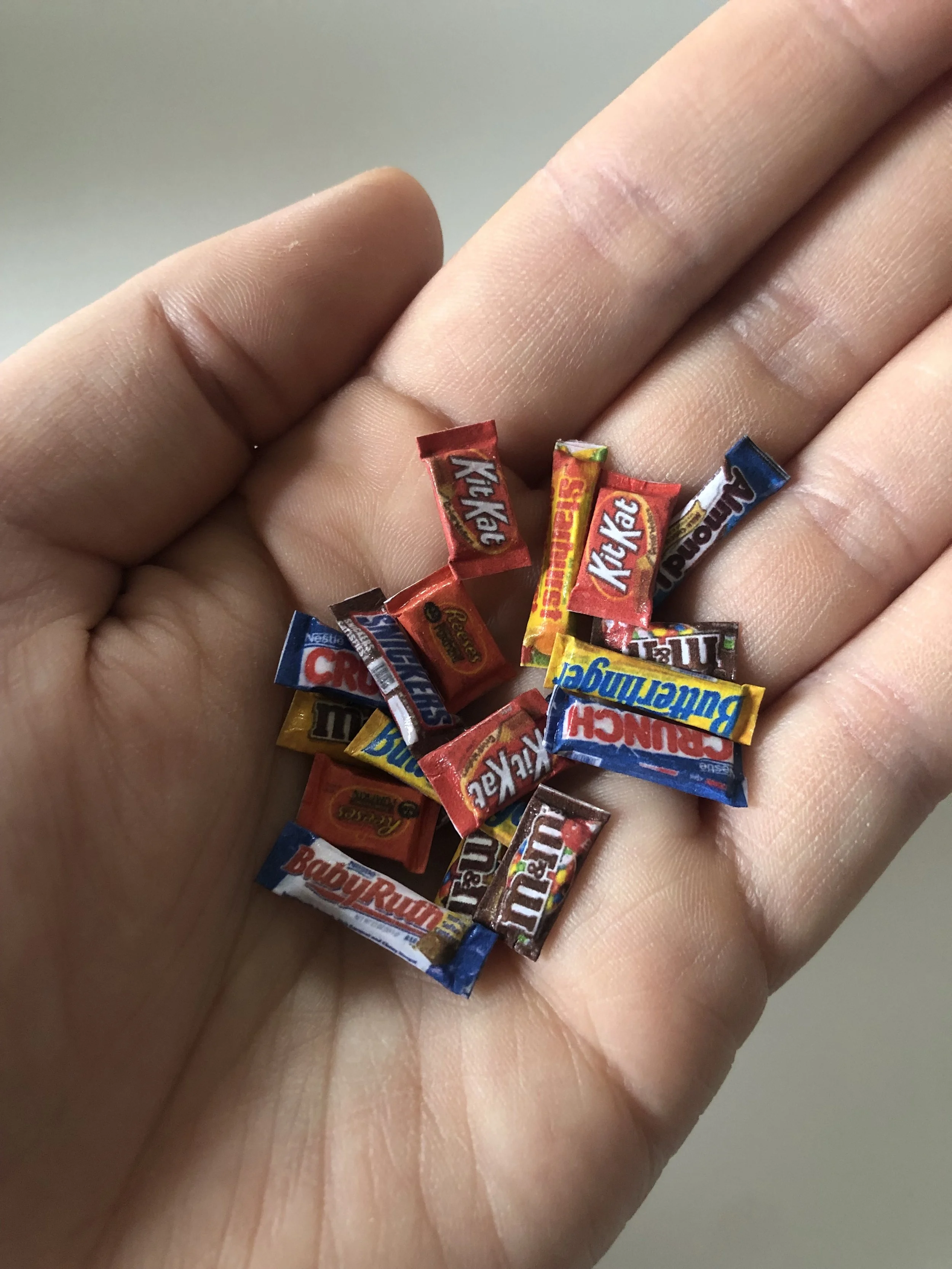 Close-up of a hand holding small candies wrapped in colorful packaging.