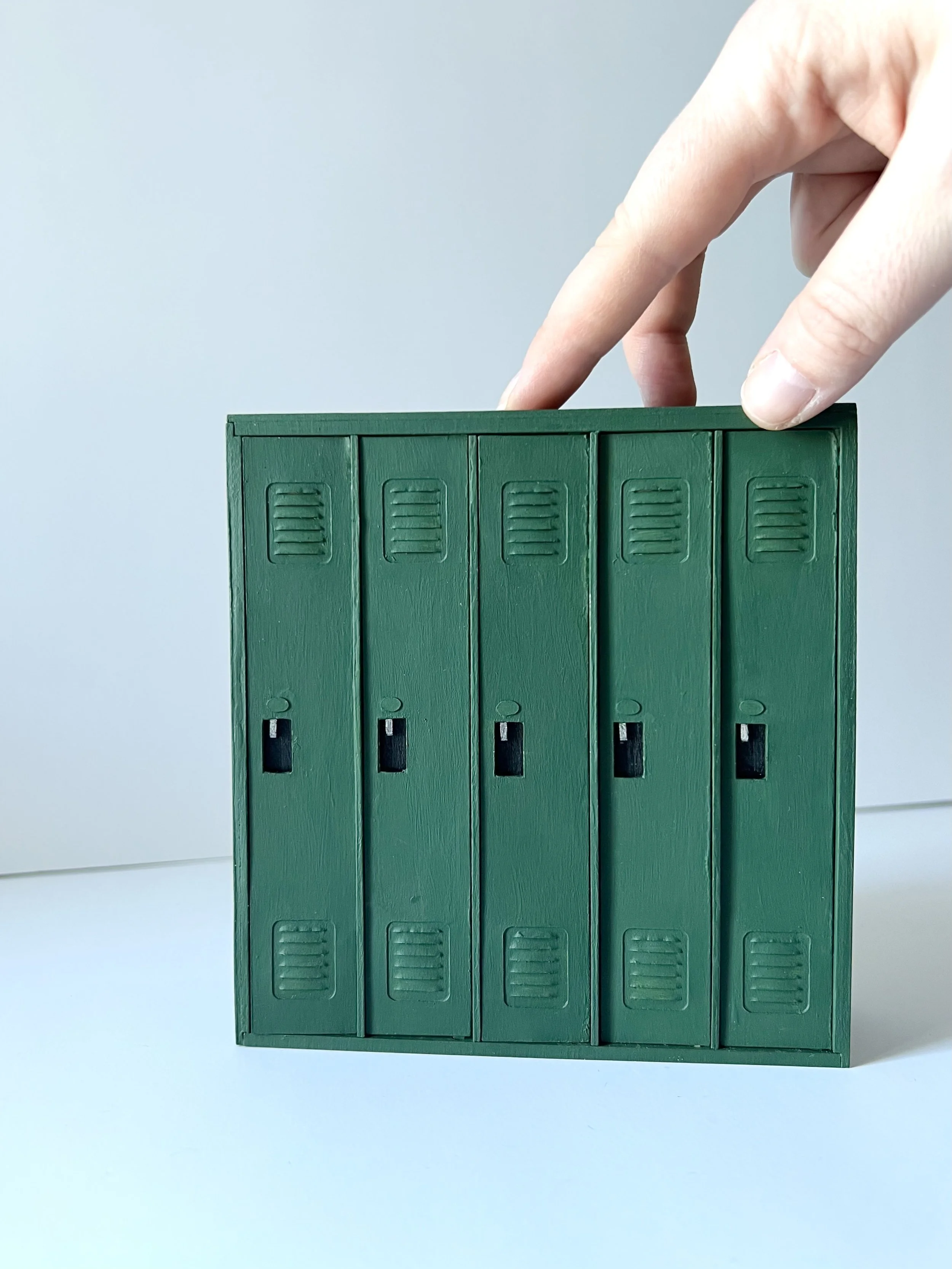 A hand placing or removing a green plastic folder with three vertical compartments against a light background.