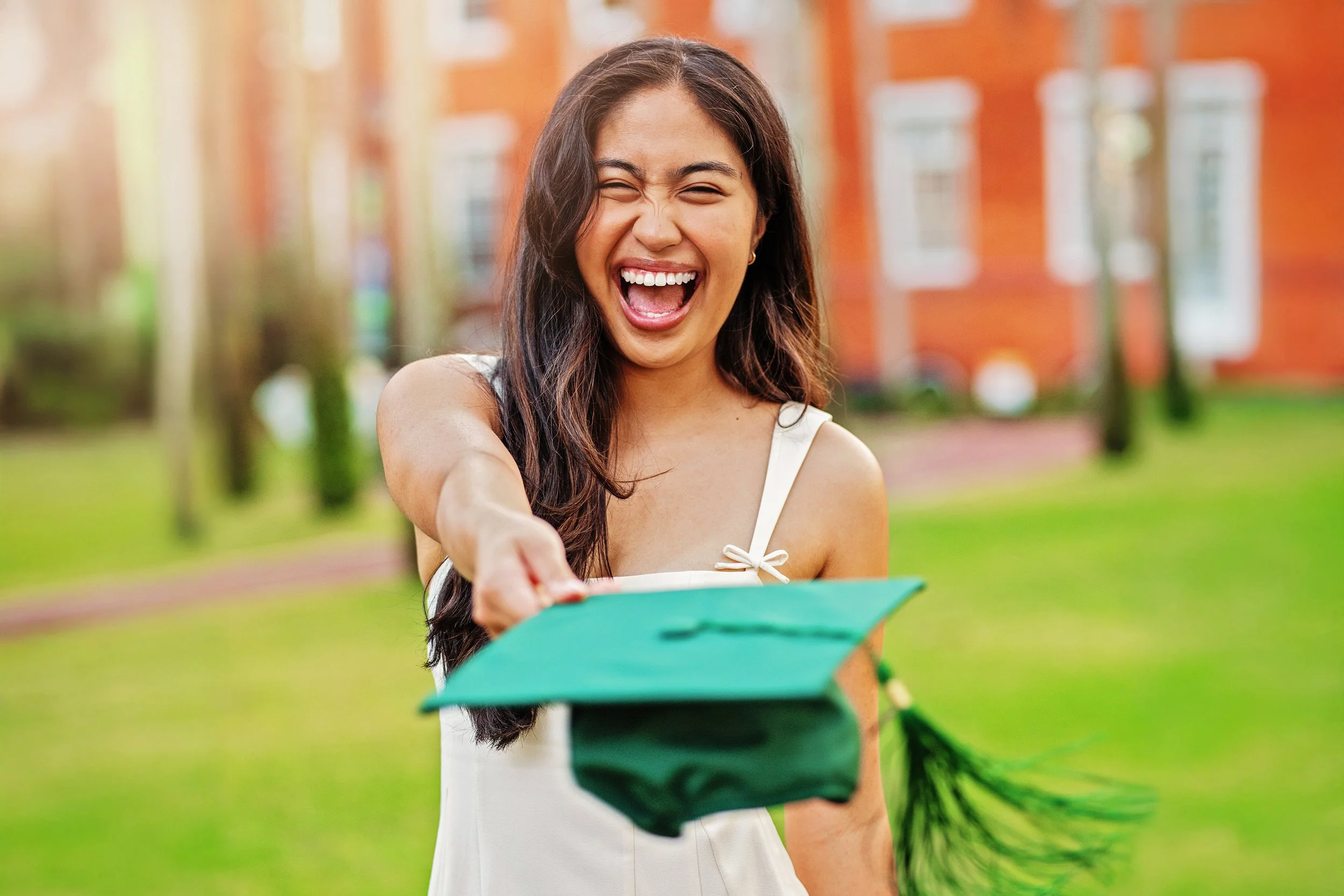 College senior posing for fun graduation session, throwing her grad cap