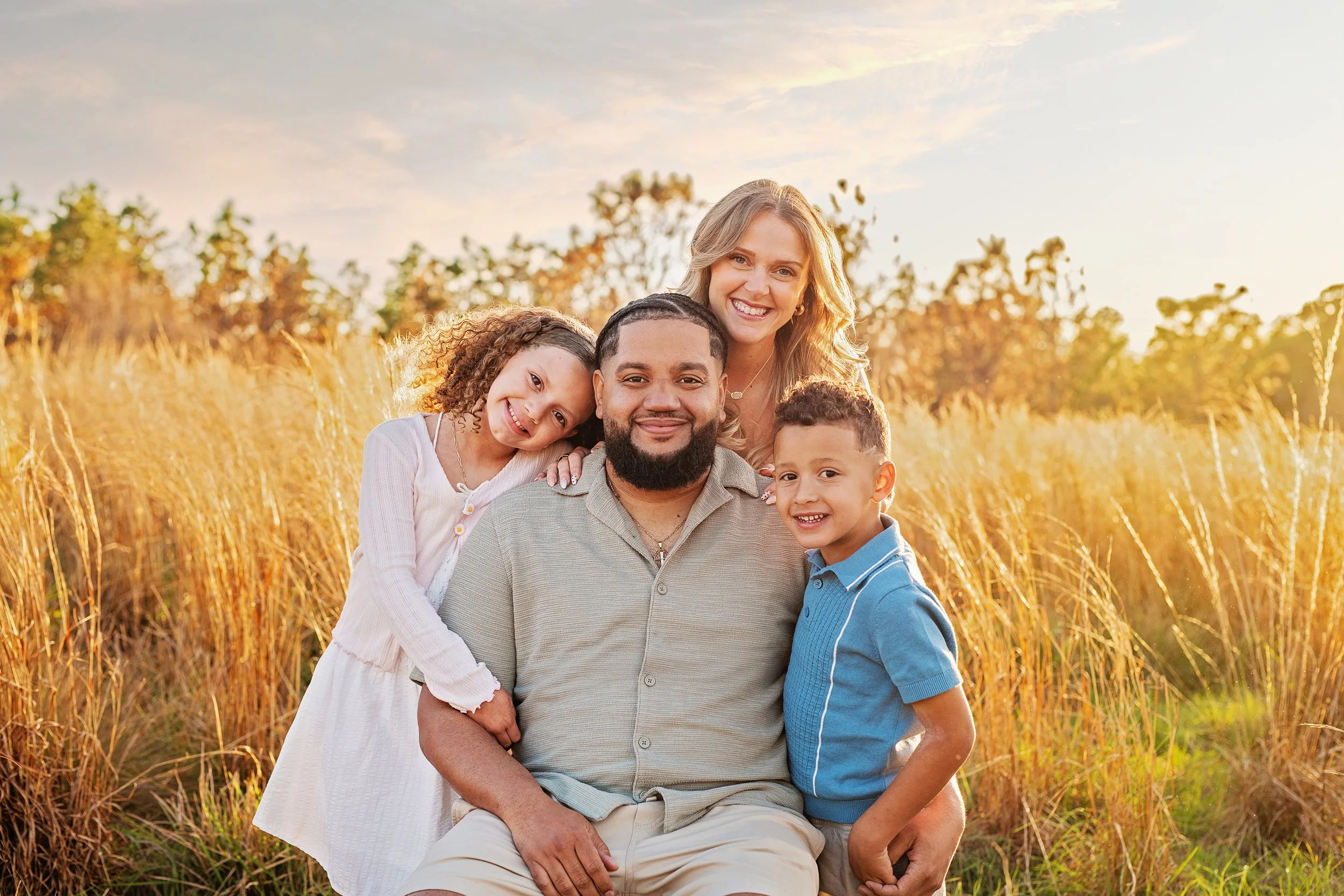Interracial family posing for family photos in tall grass with golden sunset at Lake Louisa State park florida