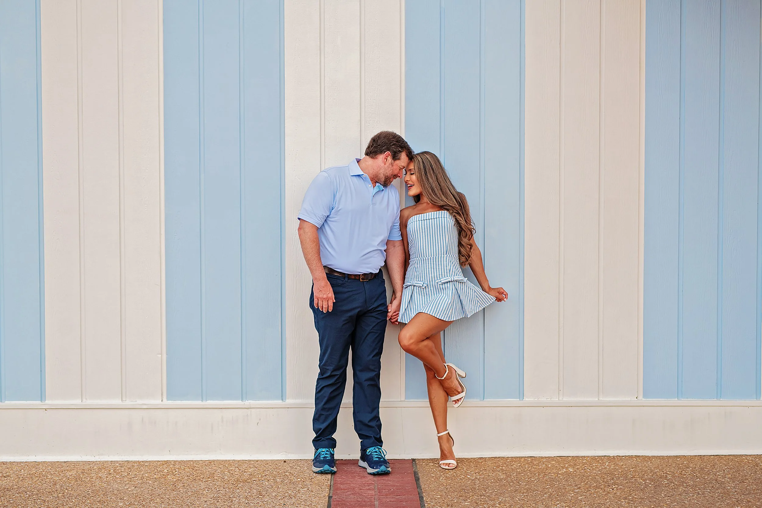 A couple on their honeymoon at Disney Boardwalk Resort in front of blue and white stripe wall
