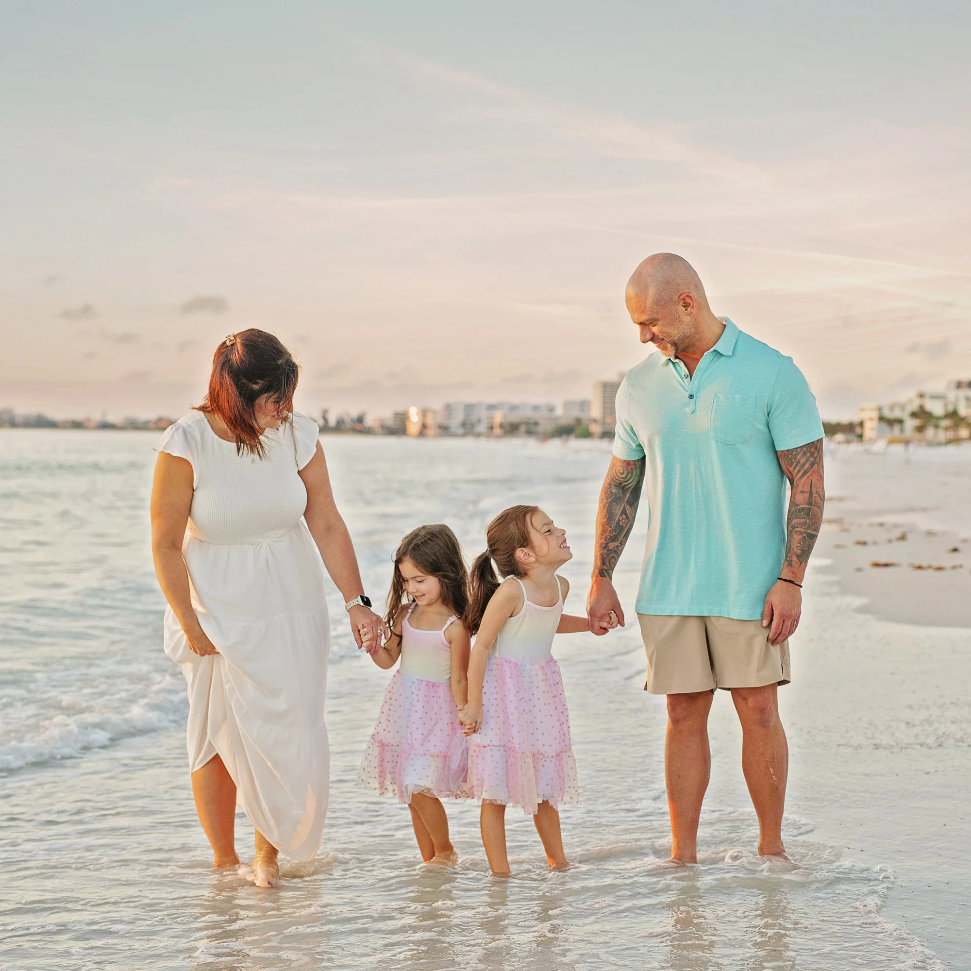 Family of four, two young girls standing in the Gulf of Mexico on Siesta Key beach for family photos