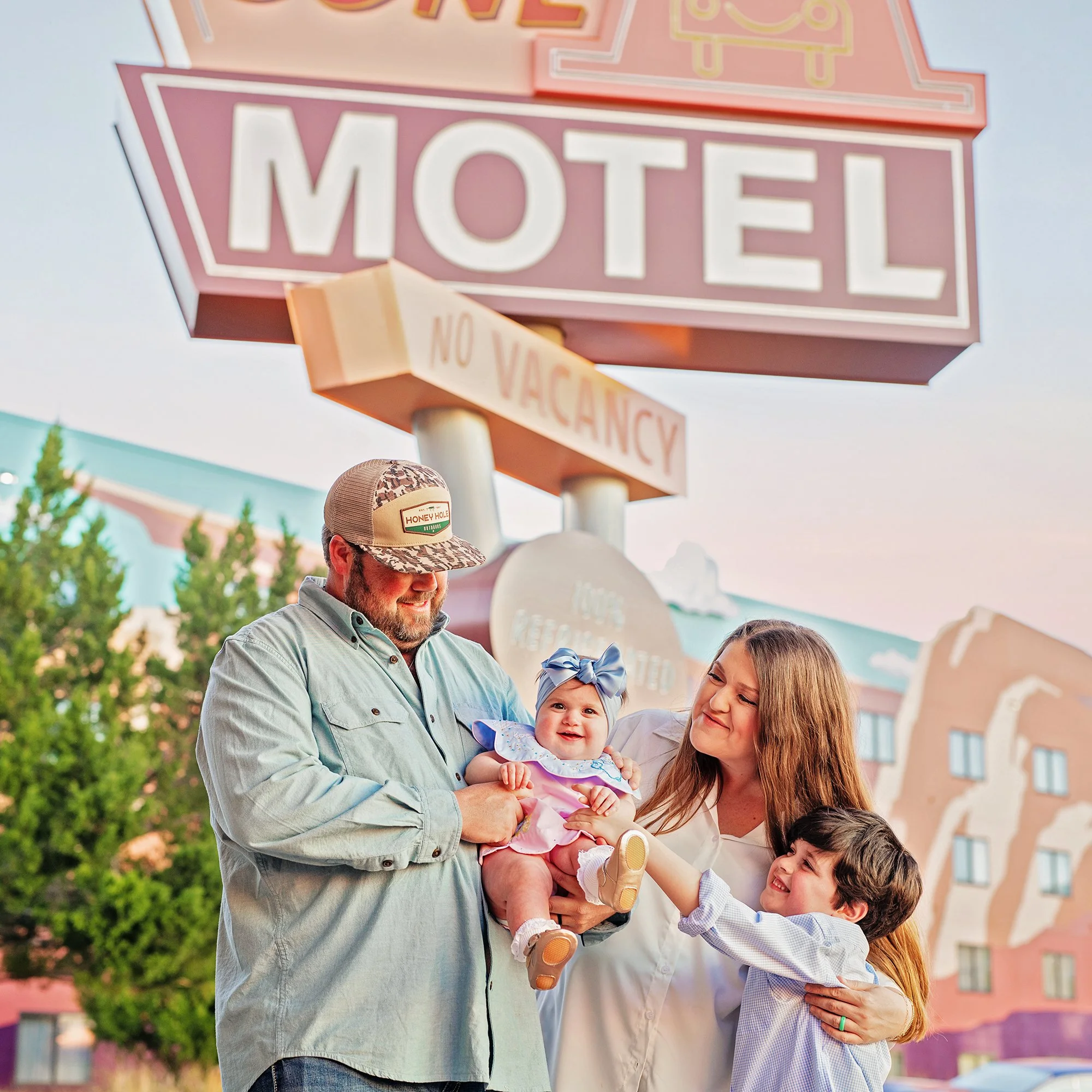 Family of four, mom, dad, son and daughter posing for a photo at Disney's Art of Animation resort, in the Disney cars section