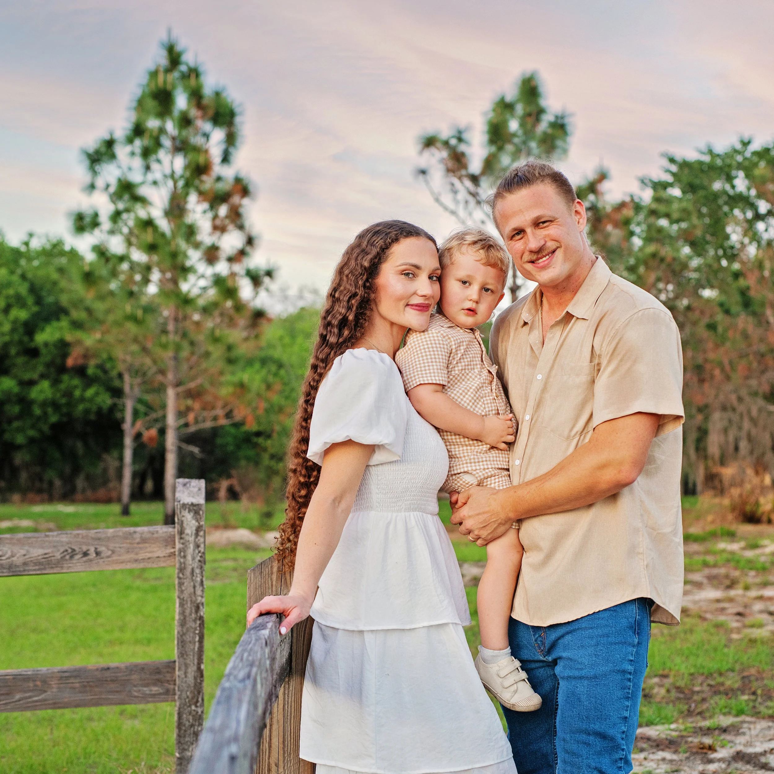 Family of 3, toddler boy, at rustic fence in Lake Louisa state park posing for a family photoshoot