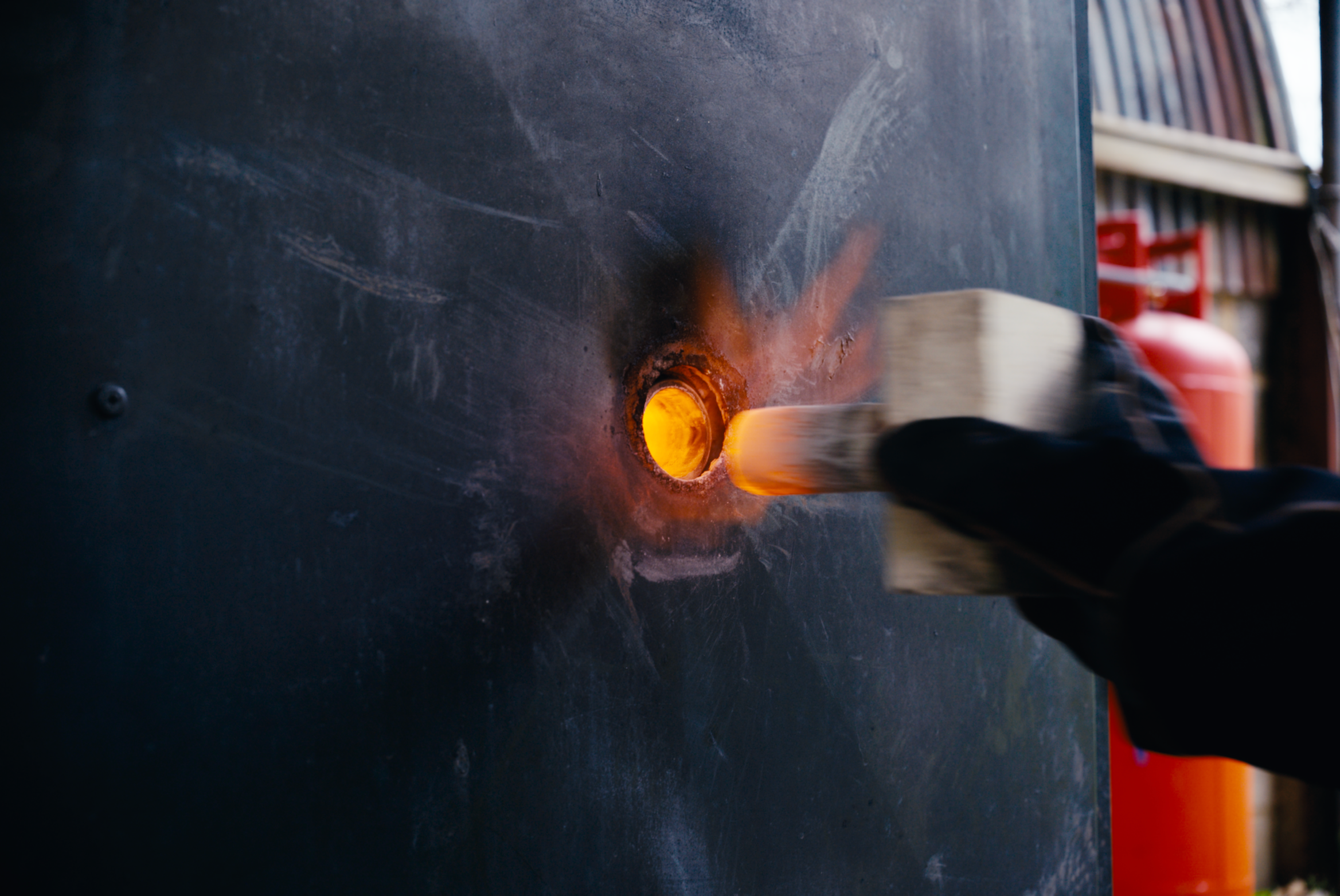 Close-up of a welding process with sparks and bright orange glow against a dark surface.
