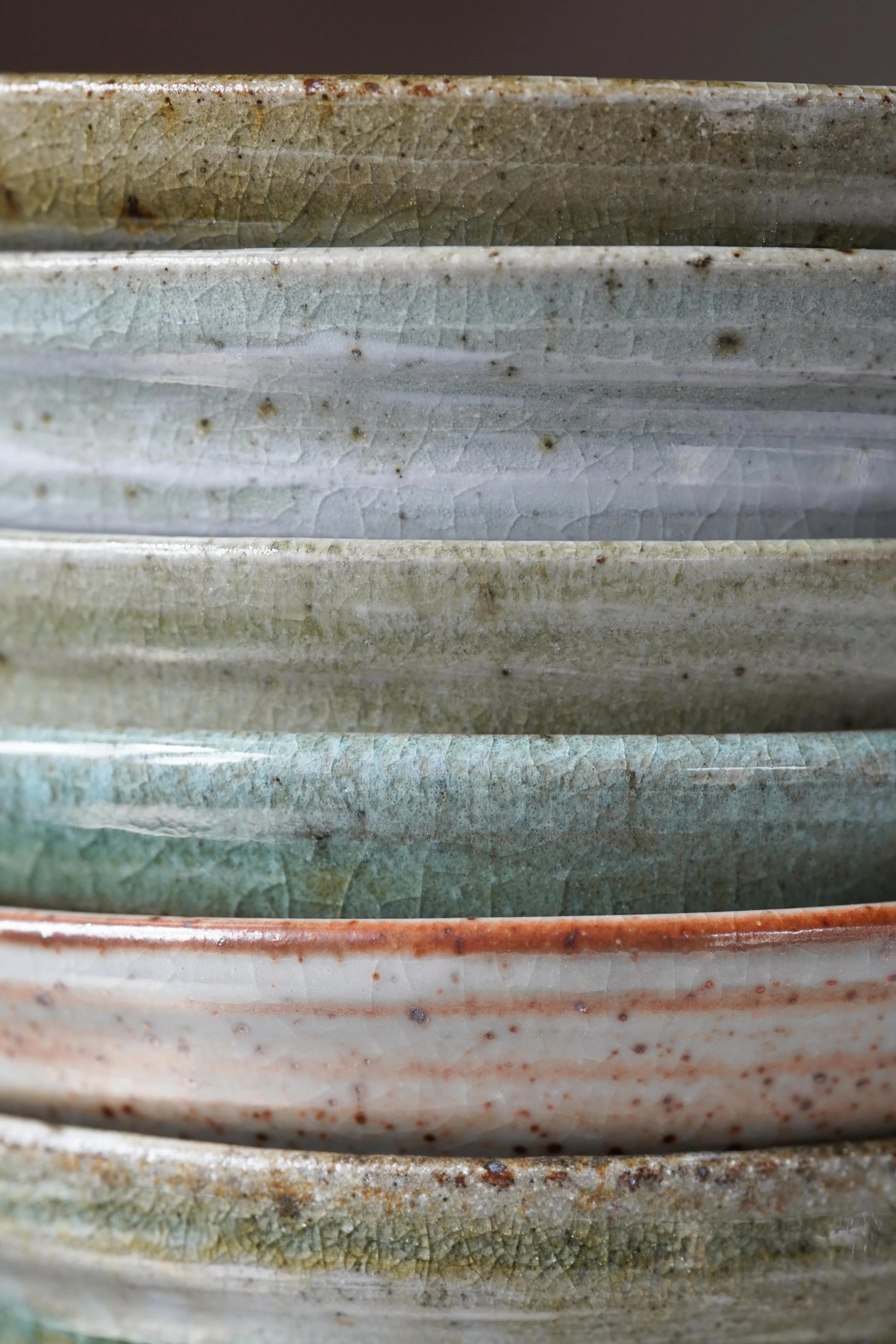 Close-up of stacked ceramic bowls with crackled glaze and earthy colors.