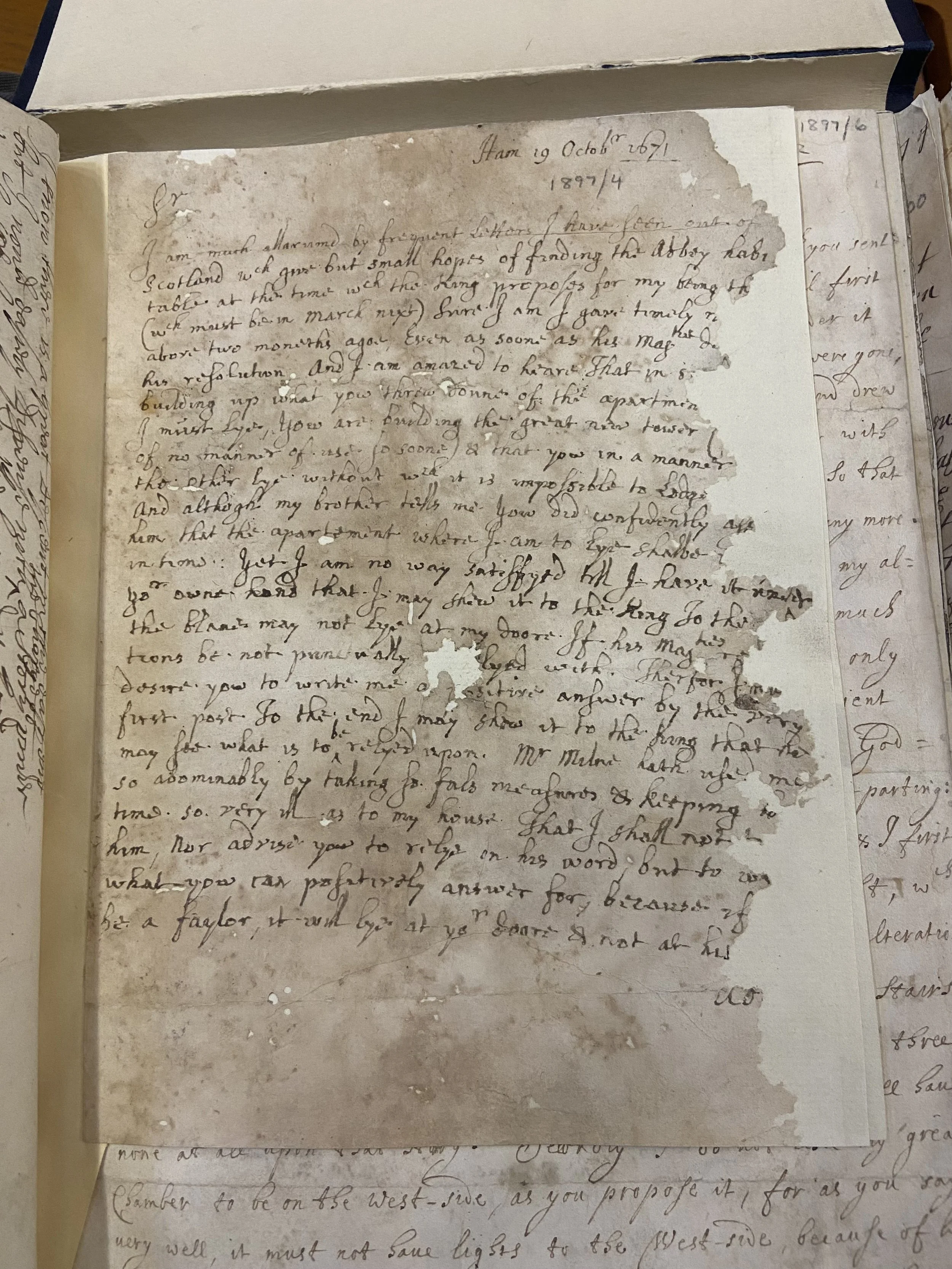A close-up photograph of an aged handwritten letter with visible tears and missing parts, written in cursive ink, dated October 19, 1897, with faintly visible text from other pages around it.