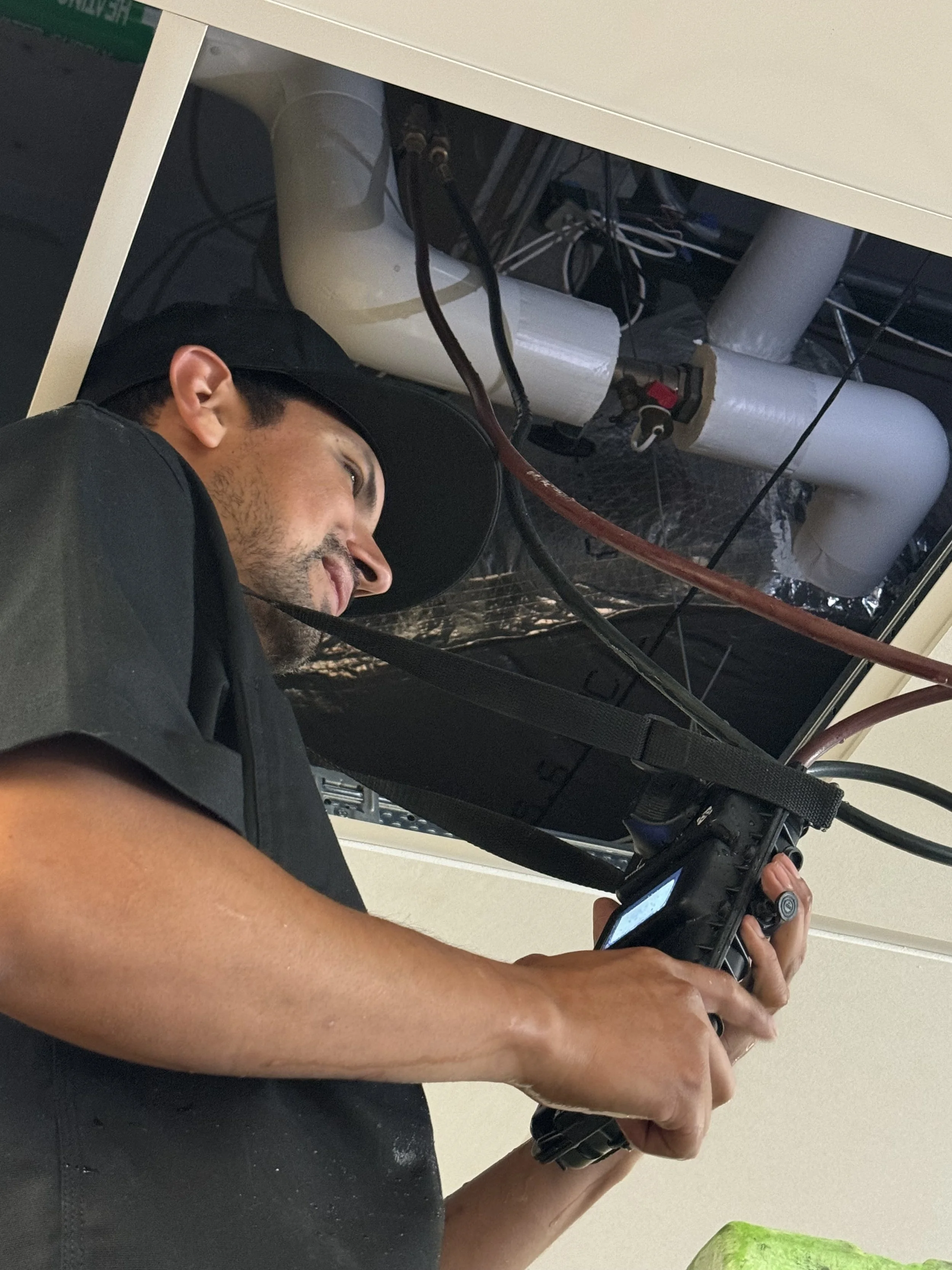 BTI Balance Technologies worker taking water measurements using water meter. Working with tools on a pipe or plumbing system, while looking at a device in his hand.