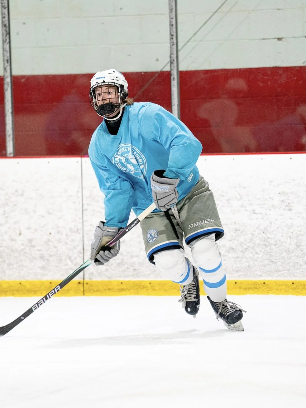 A young hockey player in a blue jersey practicing on an ice rink.