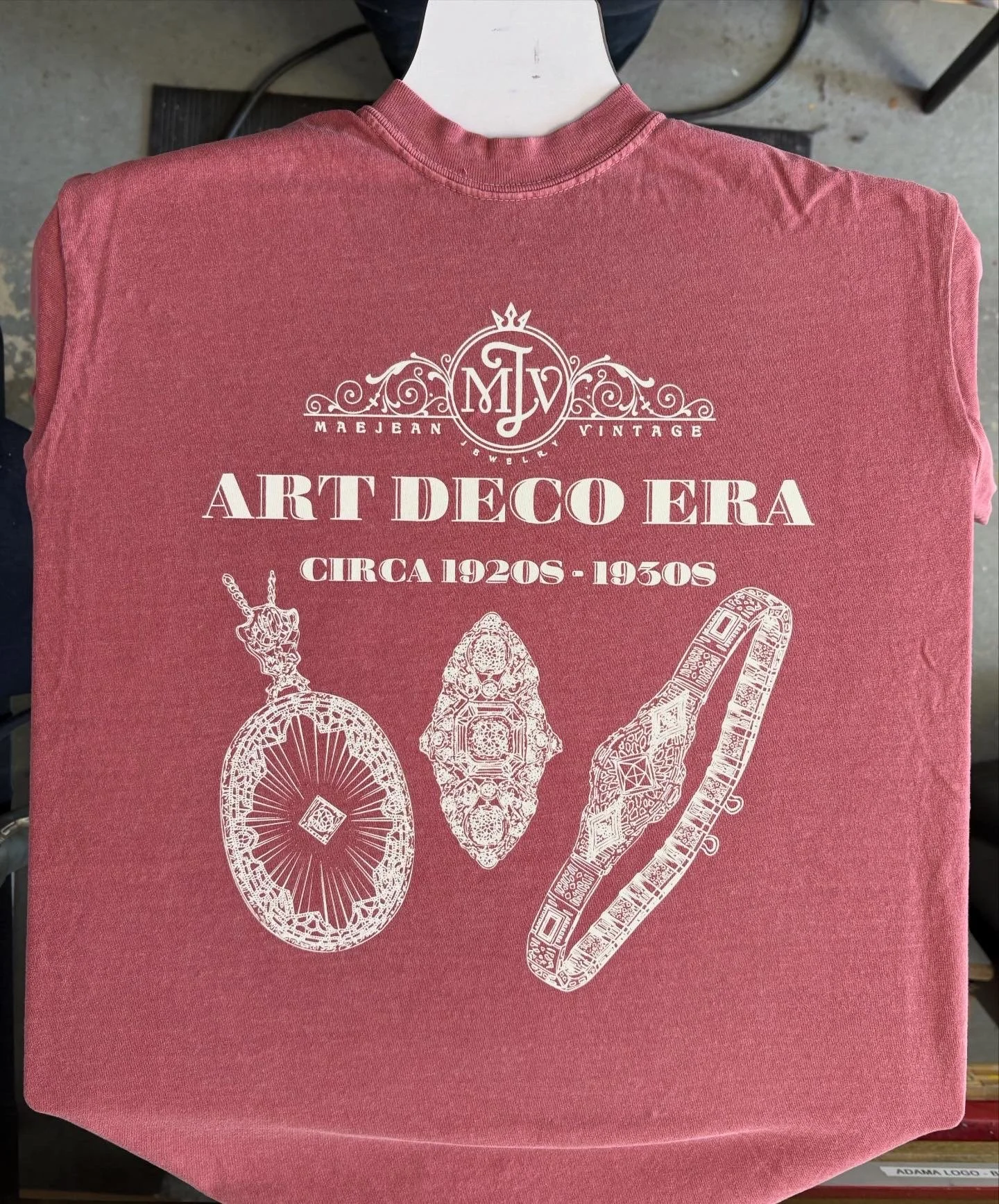 Reddish T-shirt with white line art illustrations of vintage jewelry and text about art deco era circa 1920s to 1930s.
