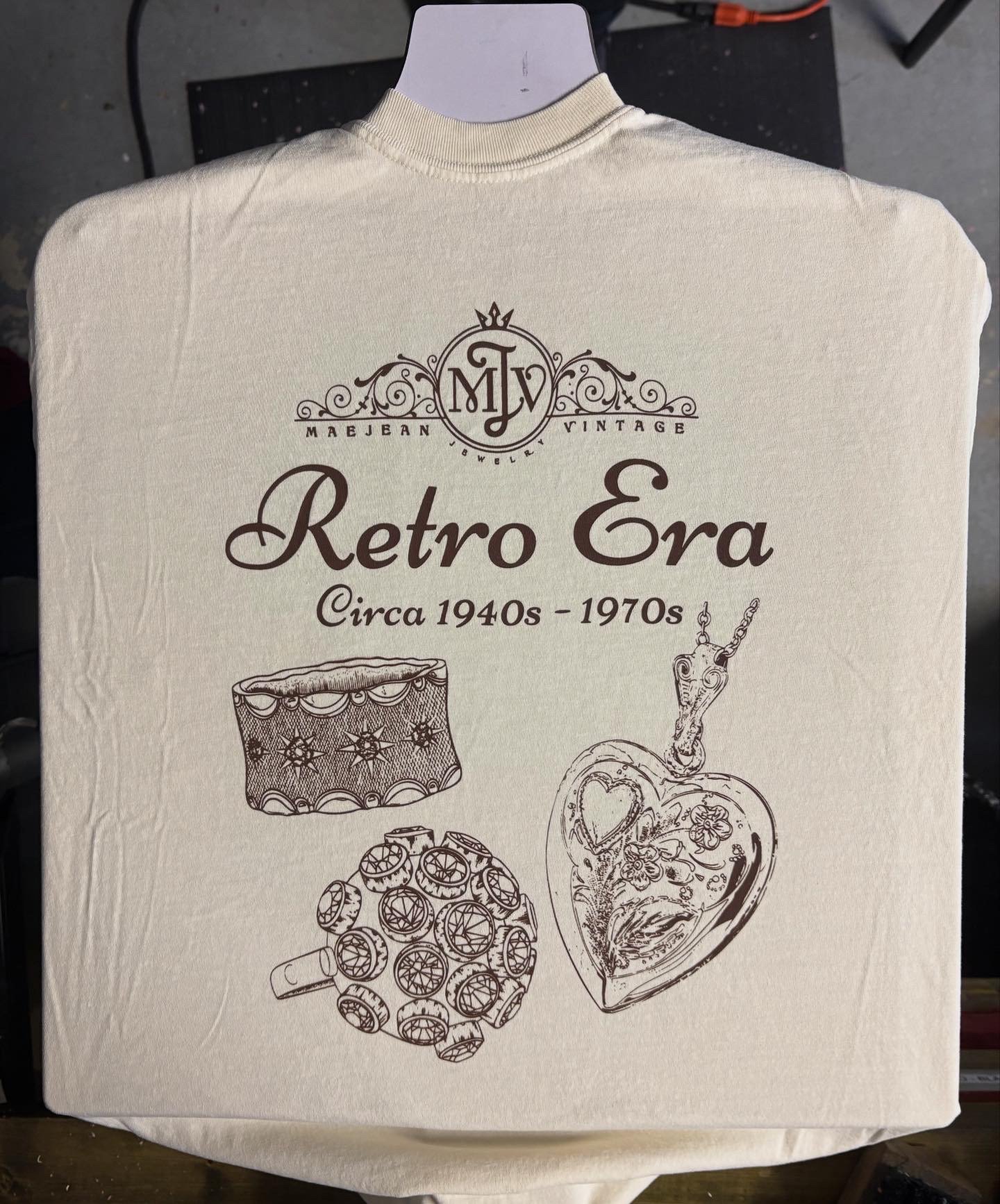A cream T-shirt with vintage-style illustrations and text about the retro era of jewelry from the 1940s through 1970s