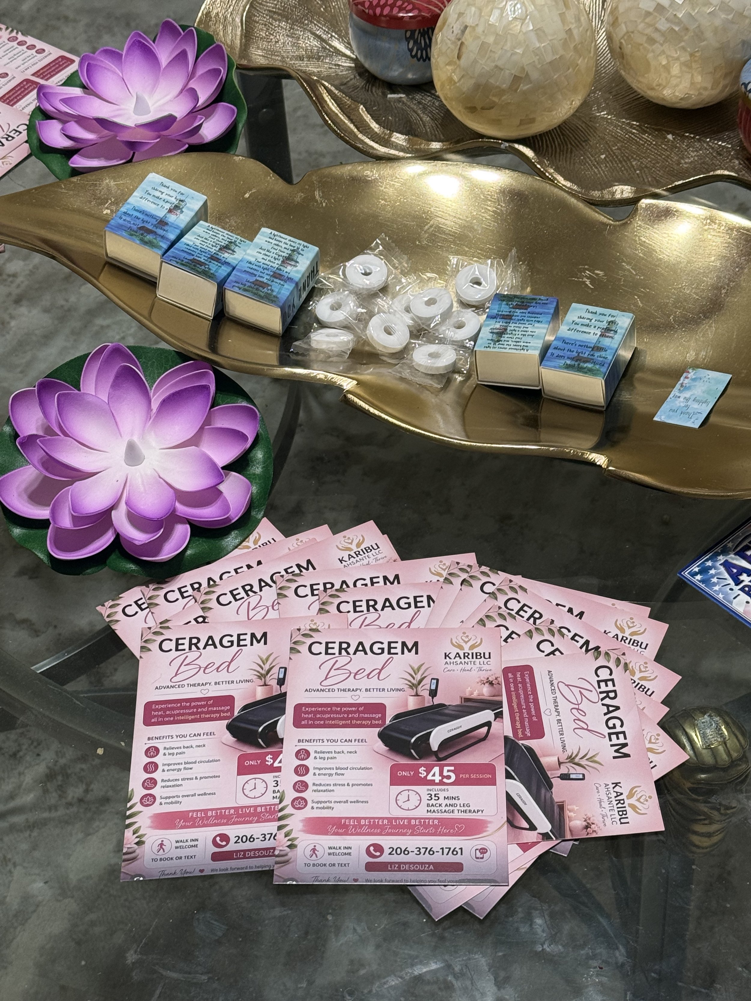 Brochures for Ceragem Bed, a massage therapy device, displayed on a table alongside flyers and decorative items like flower-shaped lights and spherical ornaments.