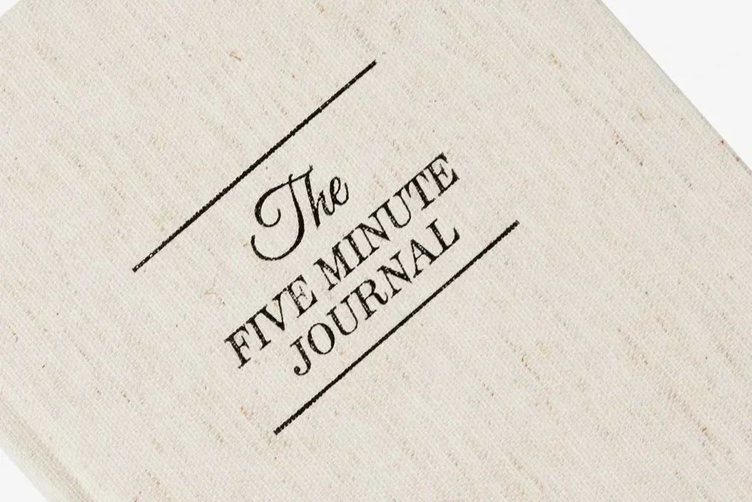 A textured background with the words, "The Five Minute Journal" printed on it.