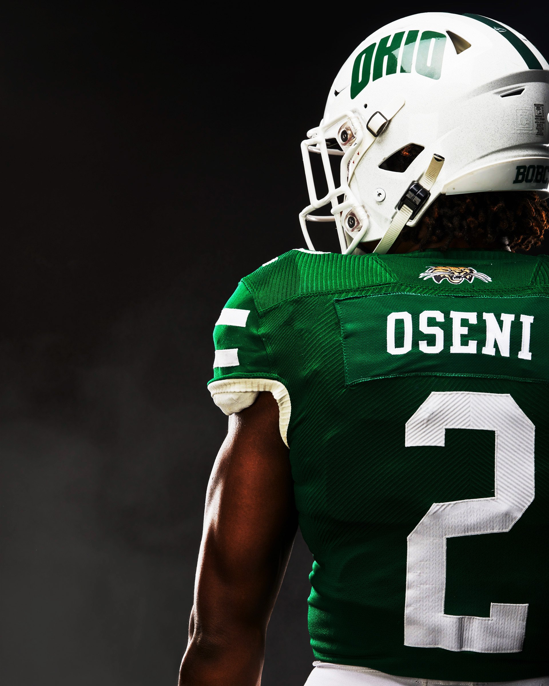 Close-up of an American football player wearing a green jersey and helmet, with the name 'OSEIN' and number 2 visible, against a dark background.