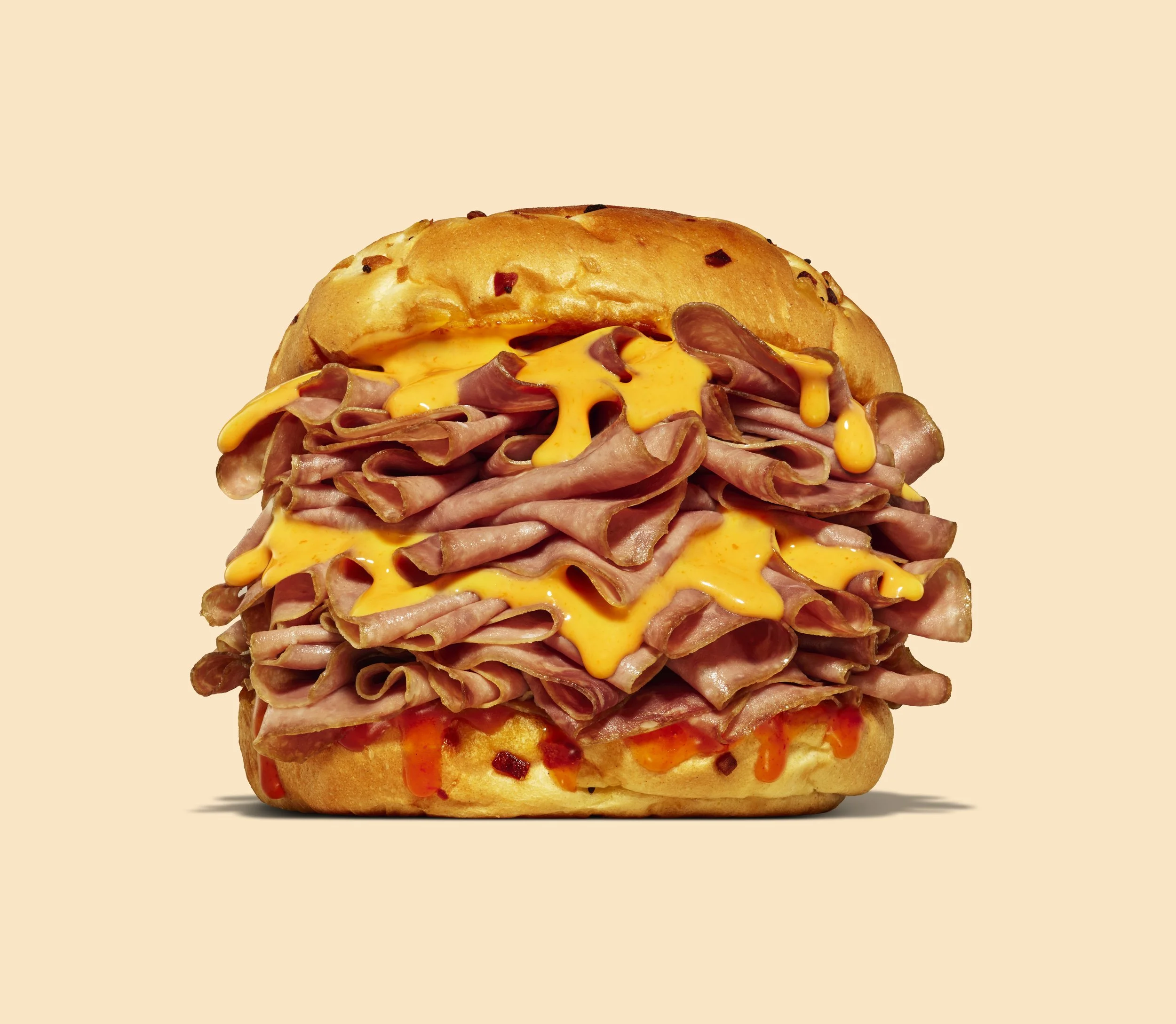 Sandwich with roast beef, melted cheese, and sauce in a bun.